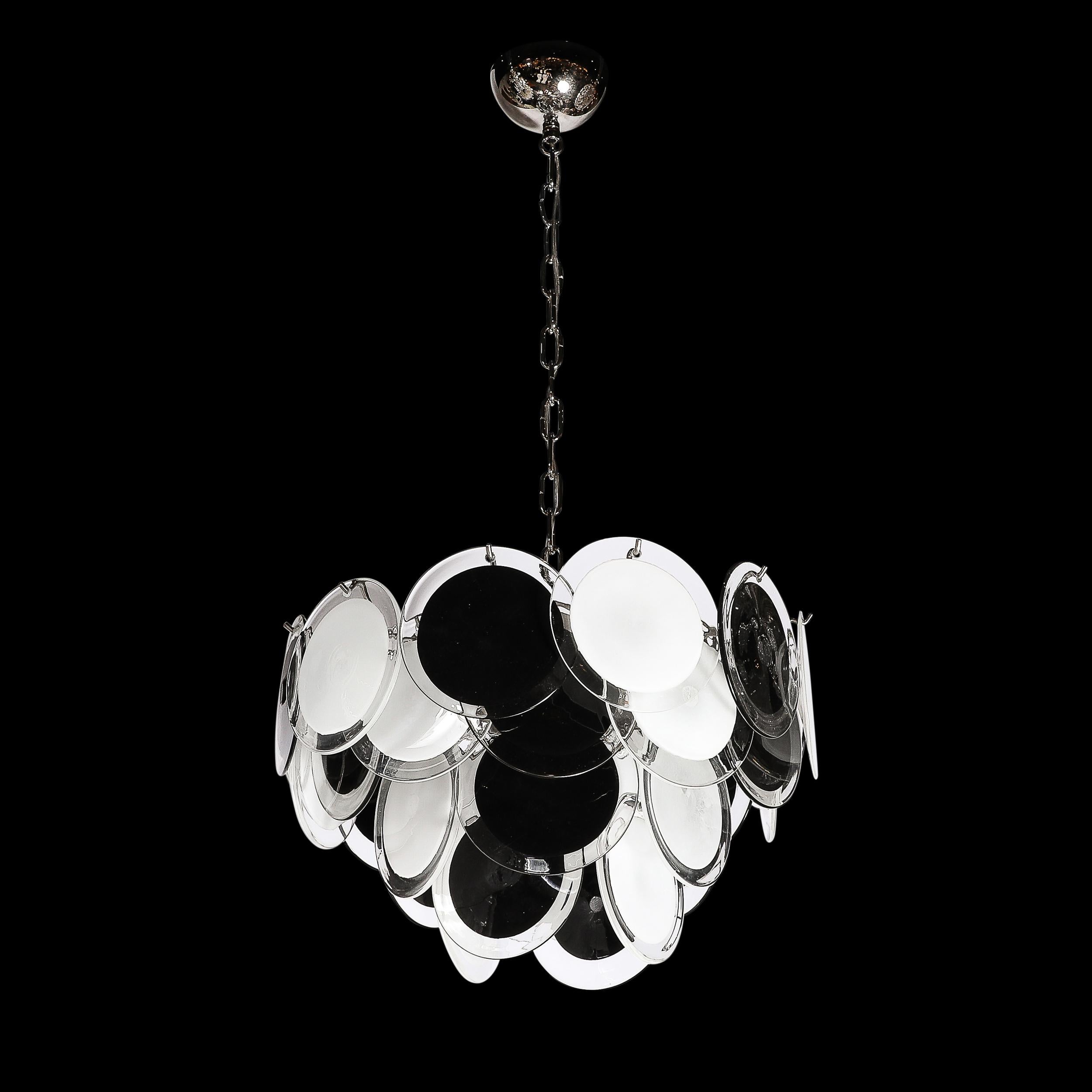 Questo elegante lampadario modernista a quattro livelli in bianco e nero soffiato a bocca di Murano proviene dall'Italia nel XXI secolo. Presenta quattro livelli di dischi sospesi in vetro di Murano soffiato a mano, con bordi esterni traslucidi su
