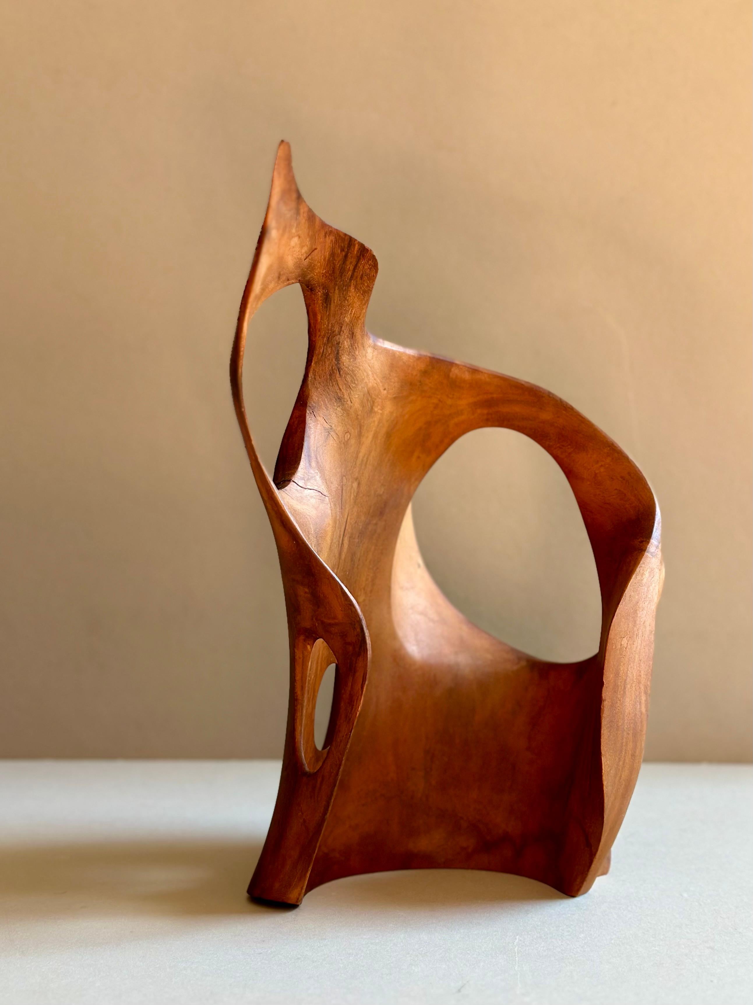 A beguiling, solid wood, tabletop sculpture with subcircular cutouts and resembling a wave or flame. Looks different at each angle and casts dramatic, sensual shadows, perfect for an area with lots of sunlight. Likely walnut. American, circa 1970.