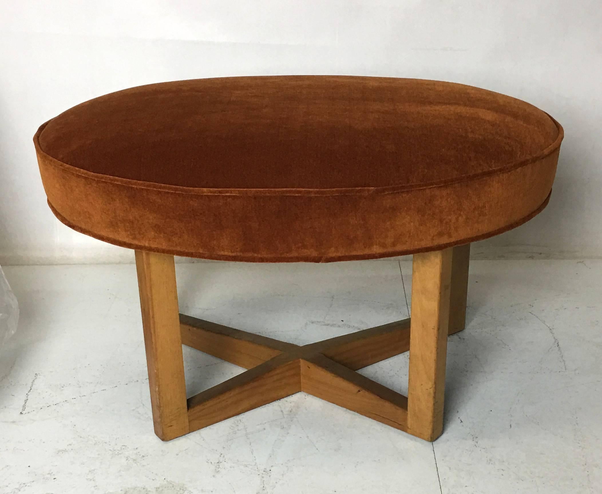 Amply scaled stool or ottoman with a free-form upholstered seat raised on a cruciform base by Paul Laszlo. The seat has been re-upholstered in luxurious heavyweight or backed JB Martin Cotton velvet. This fine piece makes for stylish occasional