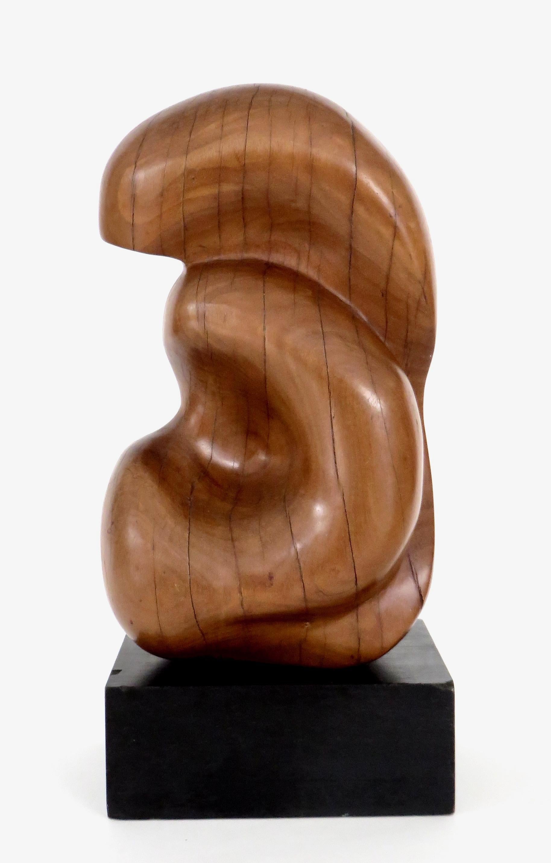 A modern abstract sculpture by an unknown artist, crafted of wood, carved and smoothed into a highly organic and bio morphic shape on a black wood plinth. 
Overall size: 7.5