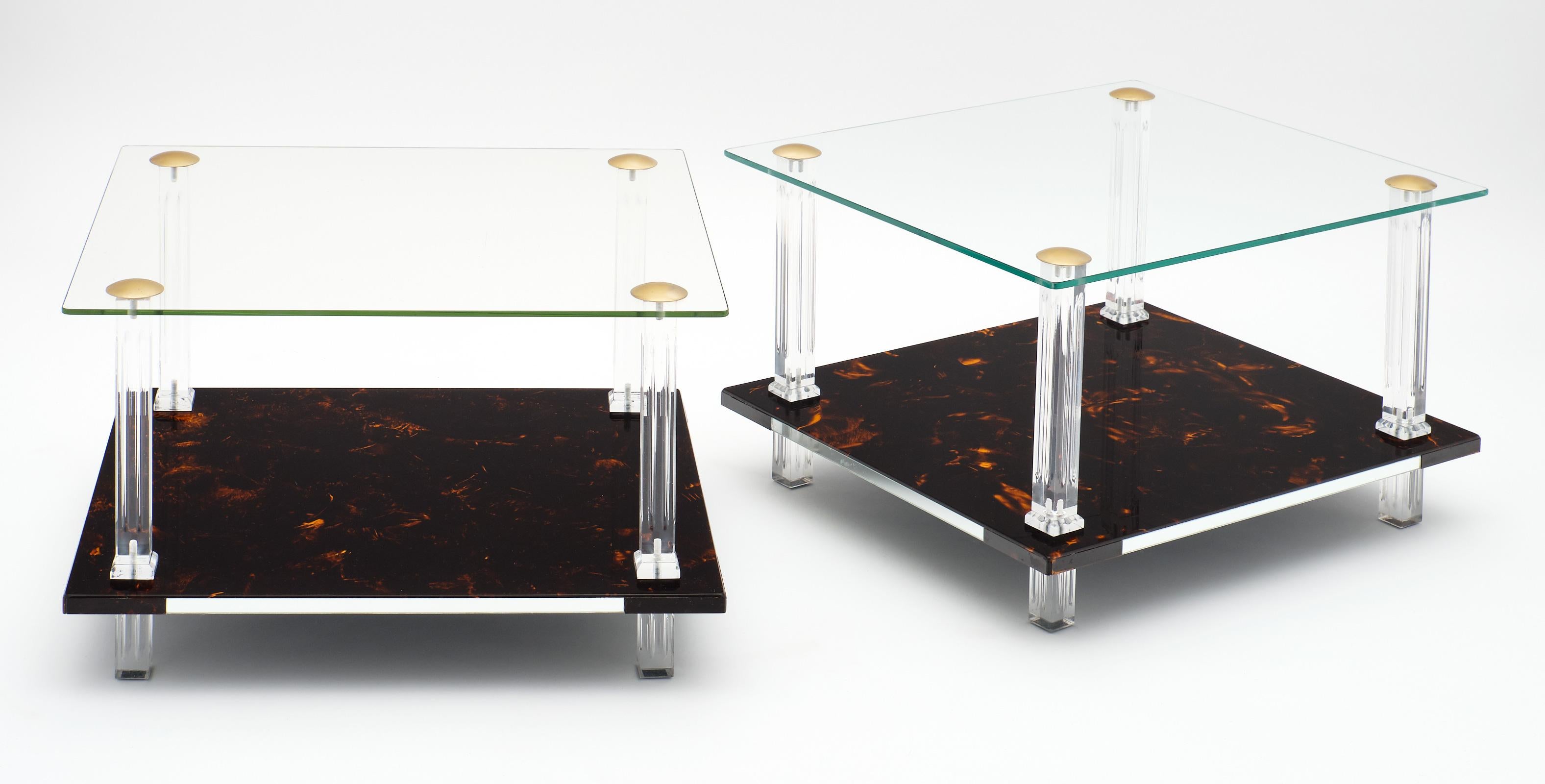 A fine French pair of modernist side tables featuring a lower shelf of “altuglass” and a glass top. The shelves are supported by four Lucite legs with brass hardware.