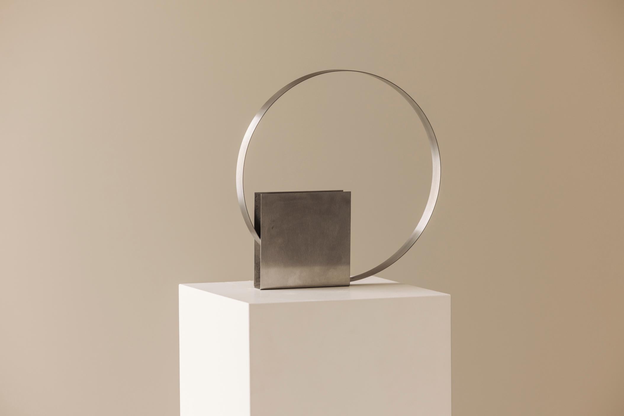 Wunderschöne französische Tischlampe aus den 1970er Jahren mit einer kühnen modernistischen Ästhetik. Das Design aus gebürstetem Metall zeichnet sich durch eine minimalistische geometrische Basis aus, die von einem perfekt ausbalancierten,