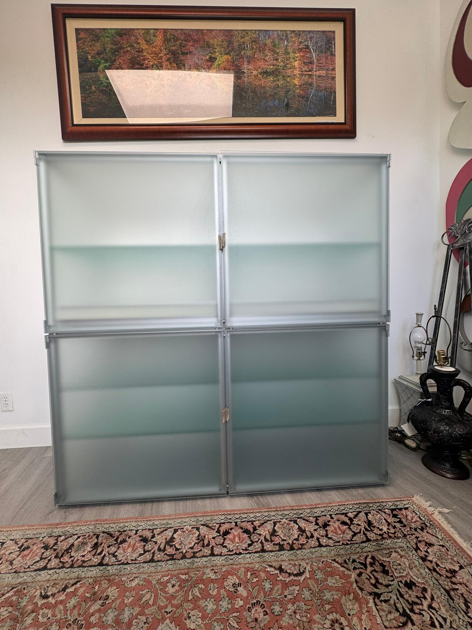 Esta elegante y moderna pieza de almacenaje de interlübke, un renombrado fabricante alemán de muebles, presenta un diseño minimalista en cristal esmerilado y aluminio, acentuado por unos tiradores de silicona únicos. Cada compartimento superior