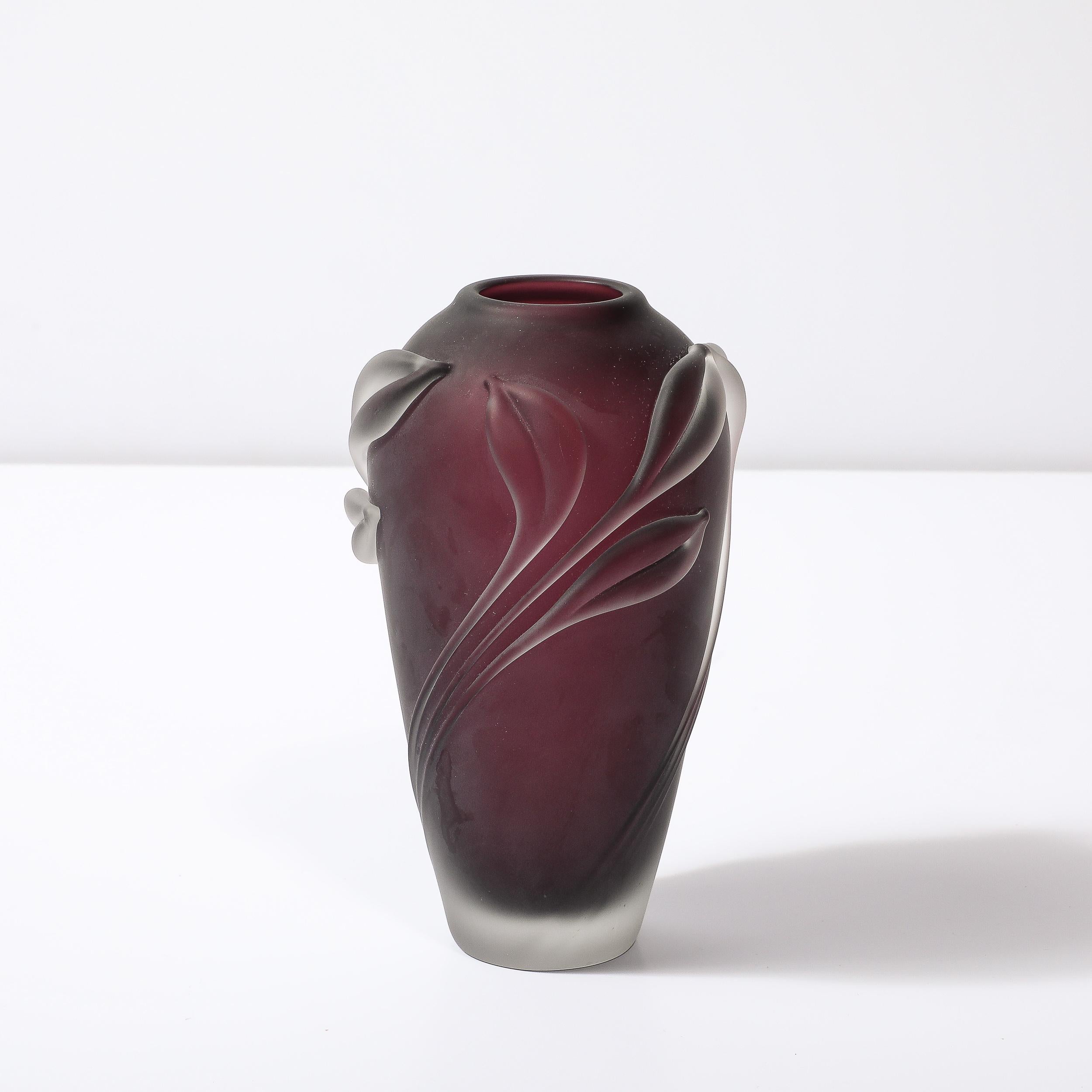 Ce charmant et sophistiqué vase moderniste en verre dépoli avec des détails floraux en relief en améthyste fumé par William Glasner est originaire des États-Unis, vers 1990. Cette pièce présente une magnifique forme effilée dans une superbe teinte