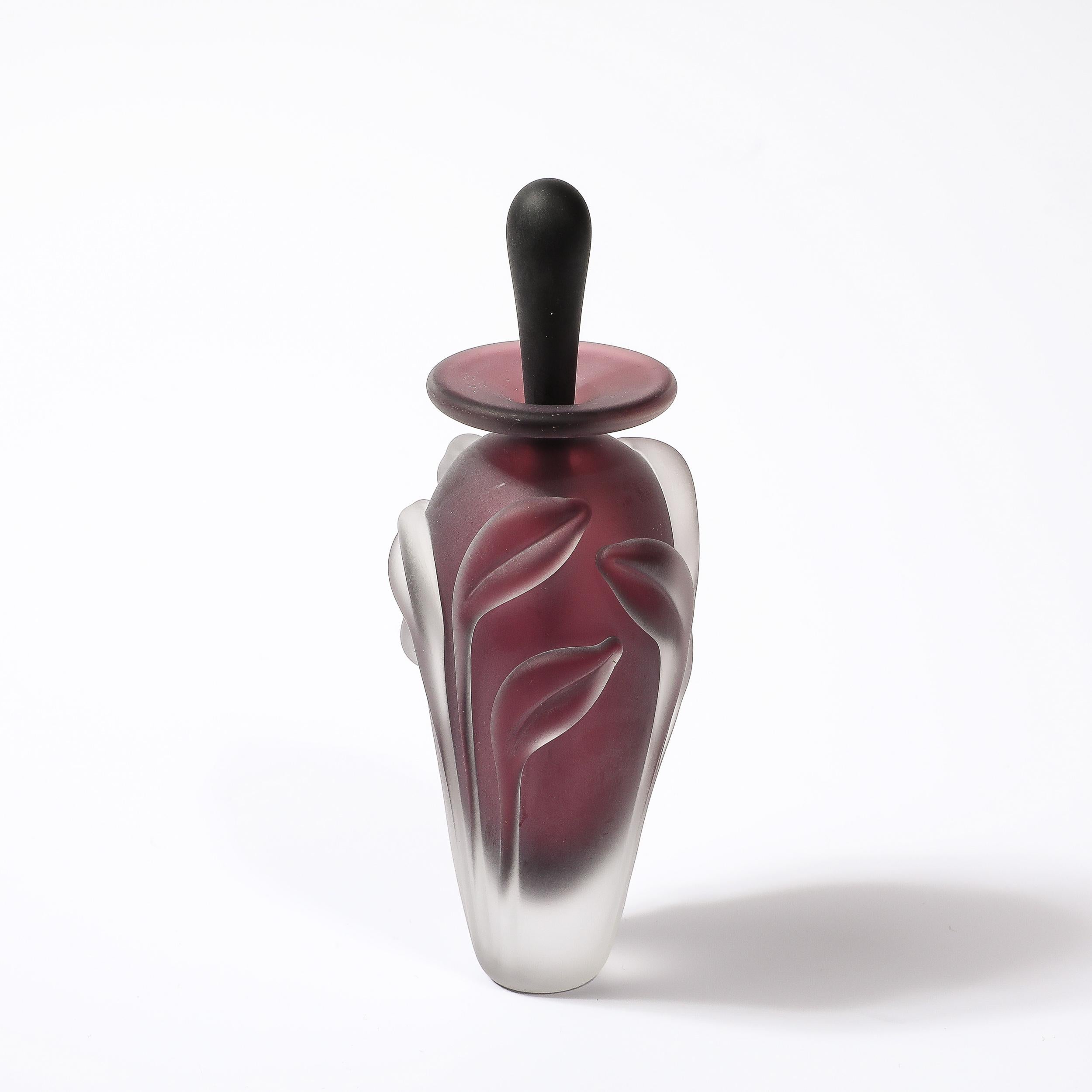 Diese schöne und raffinierte modernistische Milchglas-Parfümflasche mit floralen Reliefs in geräuchertem Amethyst von William Glasner stammt aus den Vereinigten Staaten, ca. 1990. Die schöne, konisch zulaufende Form ist in einem atemberaubenden