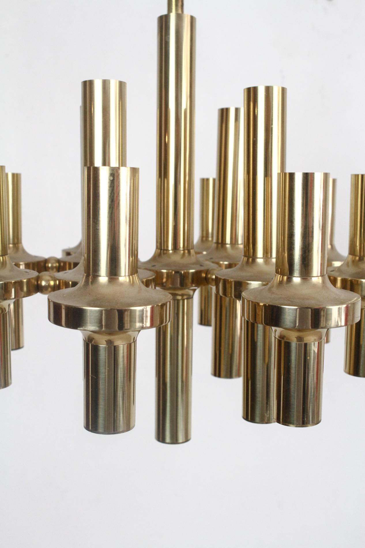 1970s modernist brass chandelier by the Italian lighting designer Gaetano Sciolari. It features 12 pieces of E14 sockets. Your choice of bulbs will create different looks; brass tipped round bulbs or tubular bulbs will compliment the fixture nicely.