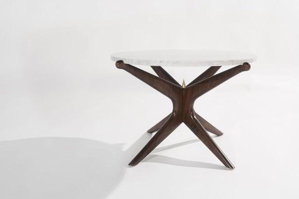 Zurückhaltende Kurven paaren sich mit unerwarteter Schärfe. Dieser Tisch aus massivem Nussbaumholz hat eine leichte Ästhetik, die auf starken, handgeformten Beinen balanciert. Mit seiner grauen, polierten Marmorplatte bietet er einen natürlichen
