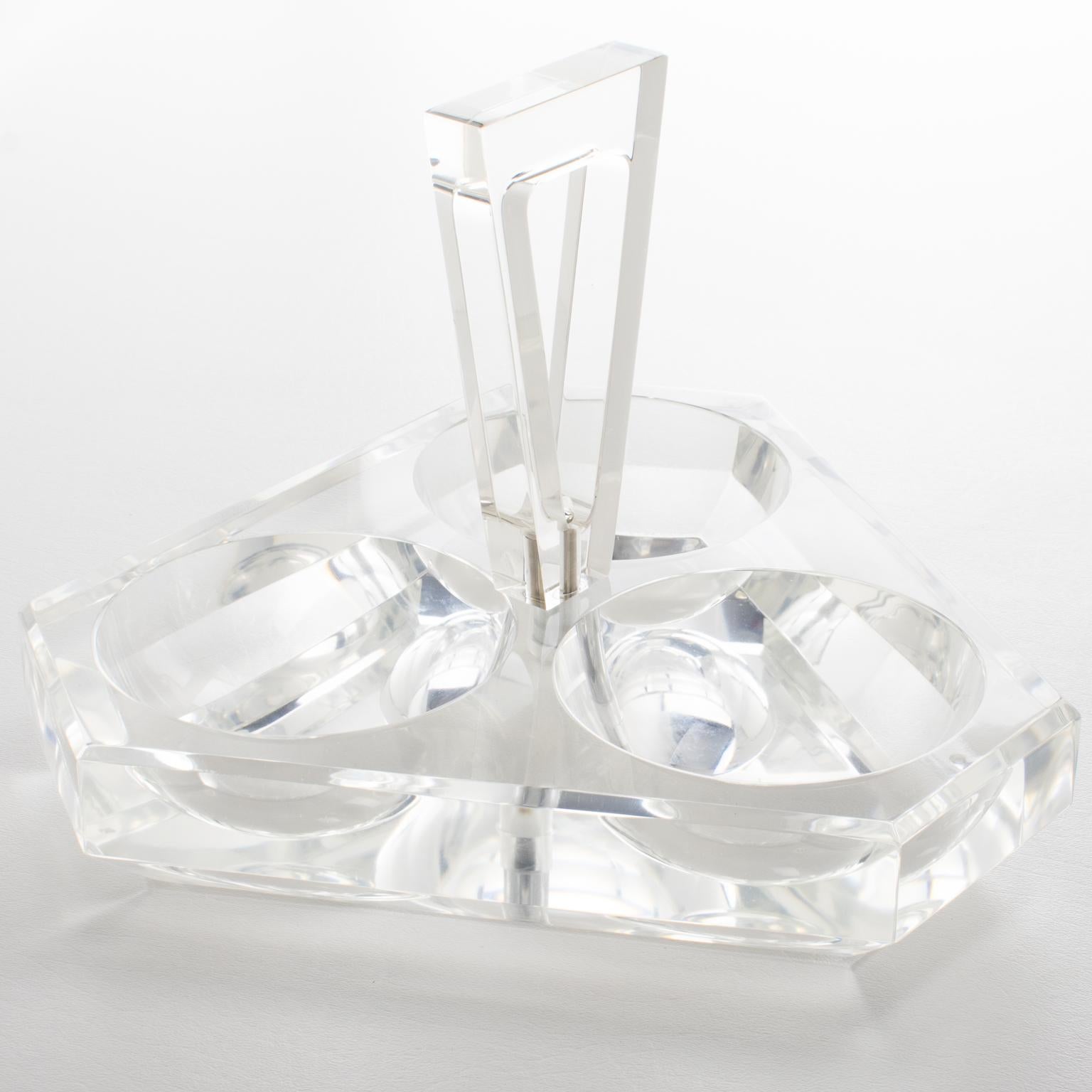 Este sofisticado cuenco, bandeja o plato para servir de Lucite o acrílico modernista de mediados de siglo fue fabricado por Grainware hacia 1970. Este centro de mesa tiene forma geométrica, tres recipientes tallados para aperitivos, aceitunas,