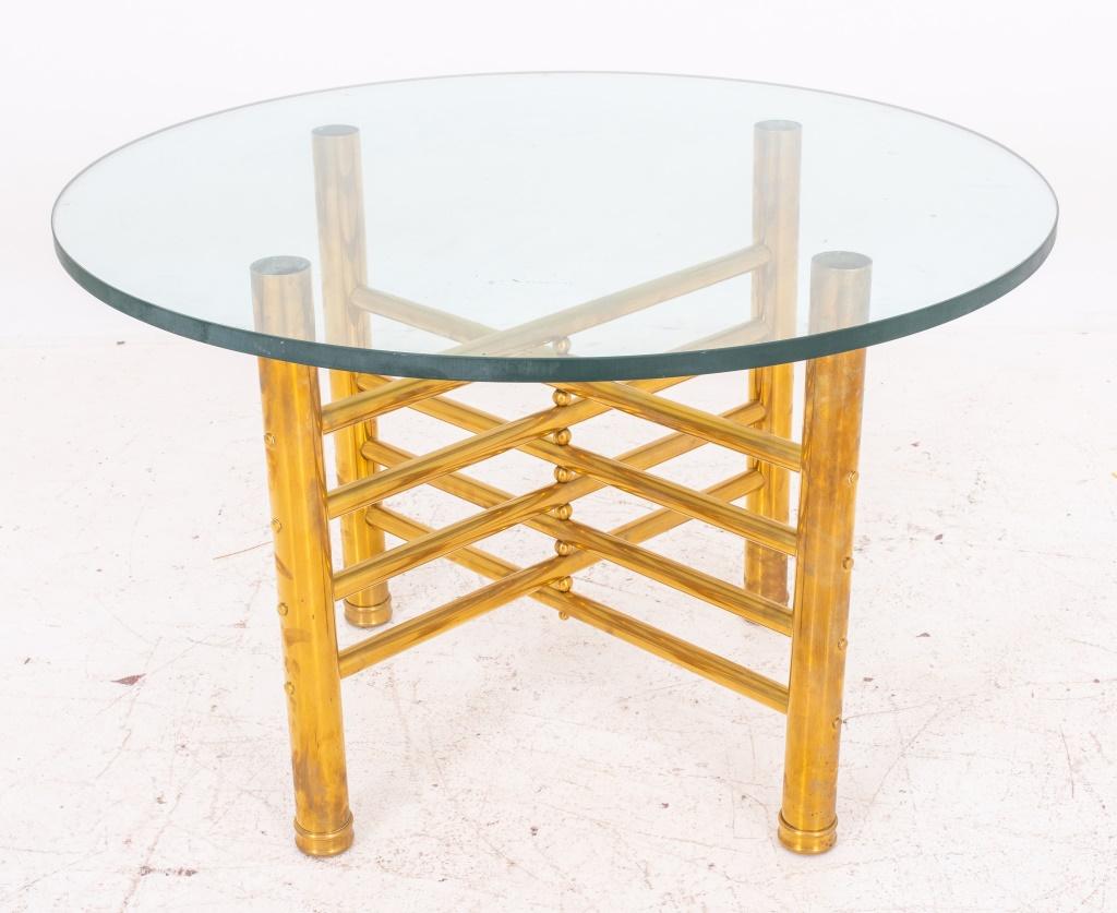 Modernist glass and brass occasional table, the circular glass top above an x-form base with columnar supports linked by ladder-form stretchers. 23