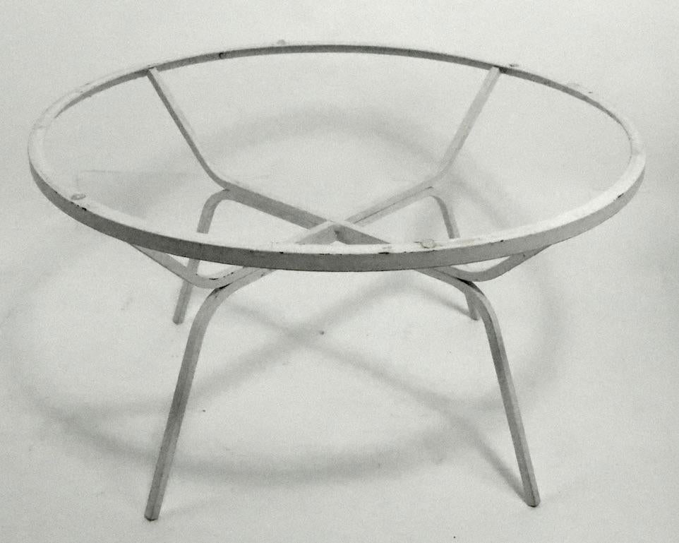 Unusual modern design occasional, side, cocktail, coffee table attributed to Salterini or possibly Woodard. The table has a circular plate glass top, and square stock wrought iron base. Currently in older white paint finish, which shows cosmetic