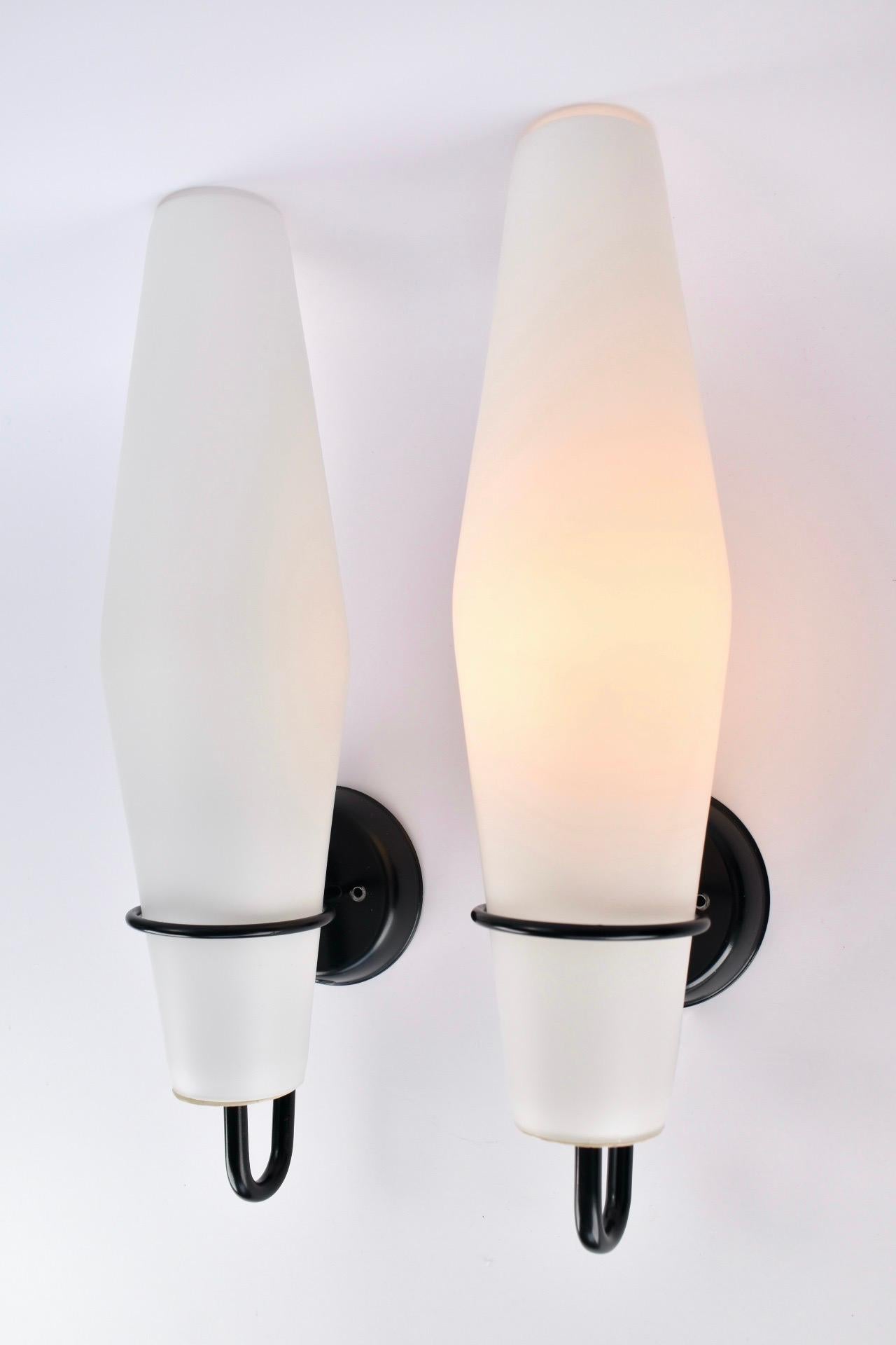 Conjunto de dos apliques modernistas de la firma holandesa RAAK. Estos apliques se diseñaron en 1958 y se conservan en muy buen estado. Algunas pequeñas salpicaduras de pintura en los soportes murales de metal negro. 