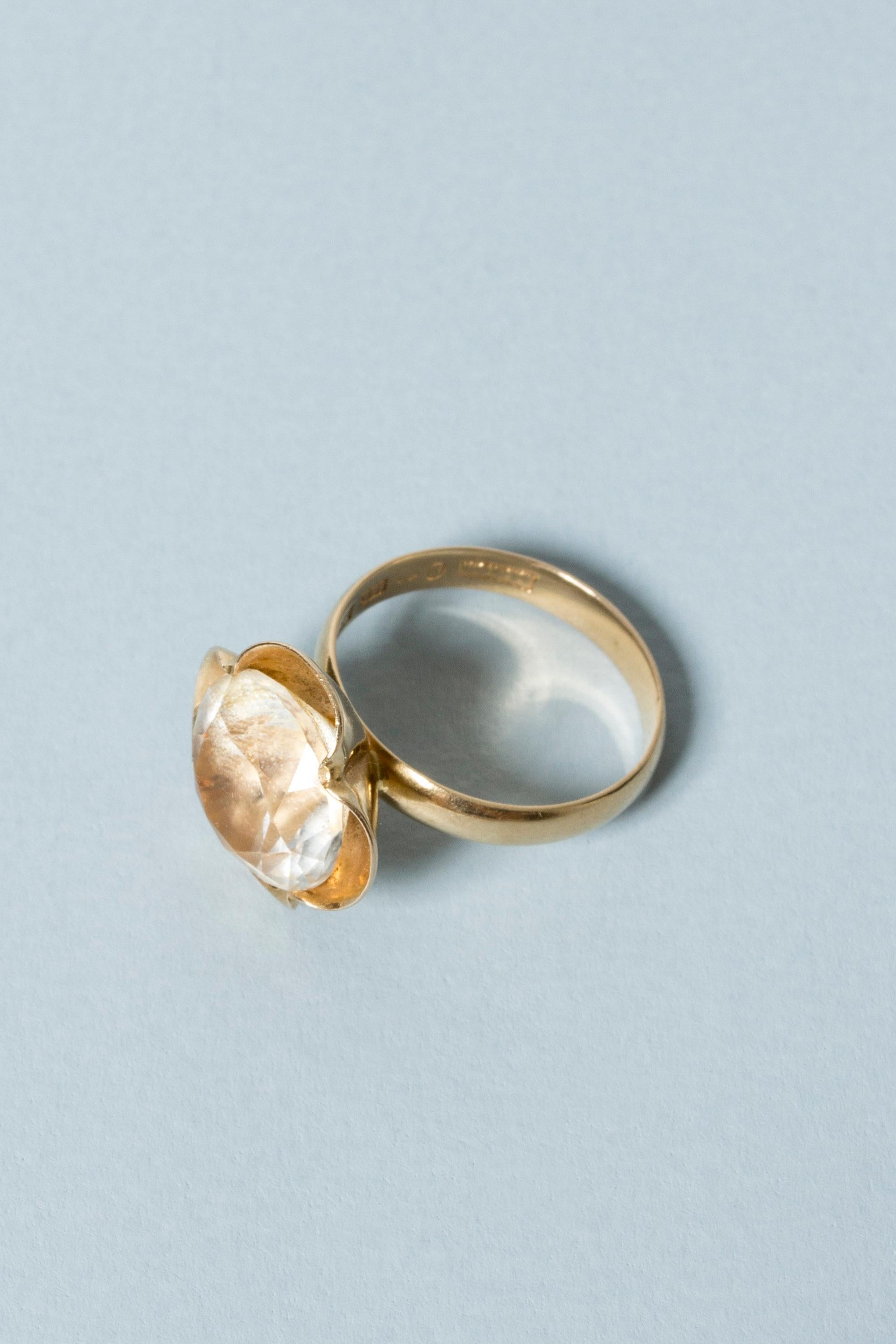 Gold ring in a sweet, modernist design from Alton. Crisp, stylized flower petals enclose a rock crystal stone. 