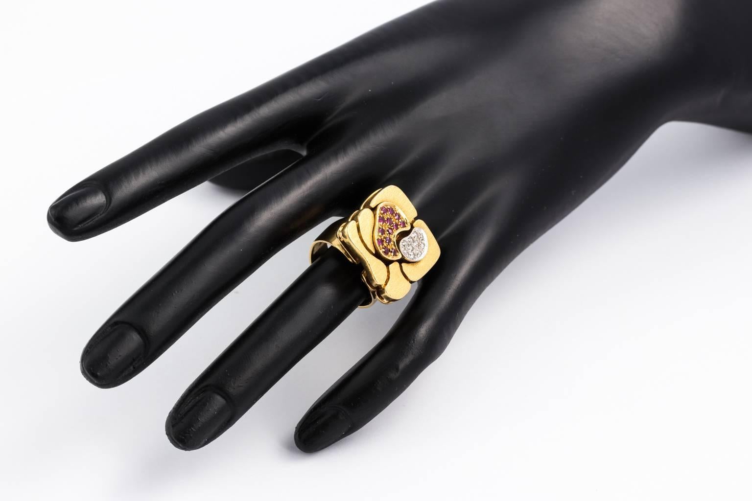 Circa 1970's hand crafted Biomorphic style brushed gold ring in 18 karat gold with pave cut diamonds and round cut rubies worked into the design of the ring that is approximately .25 carats each. The amoeba-like design is supported by a layer of