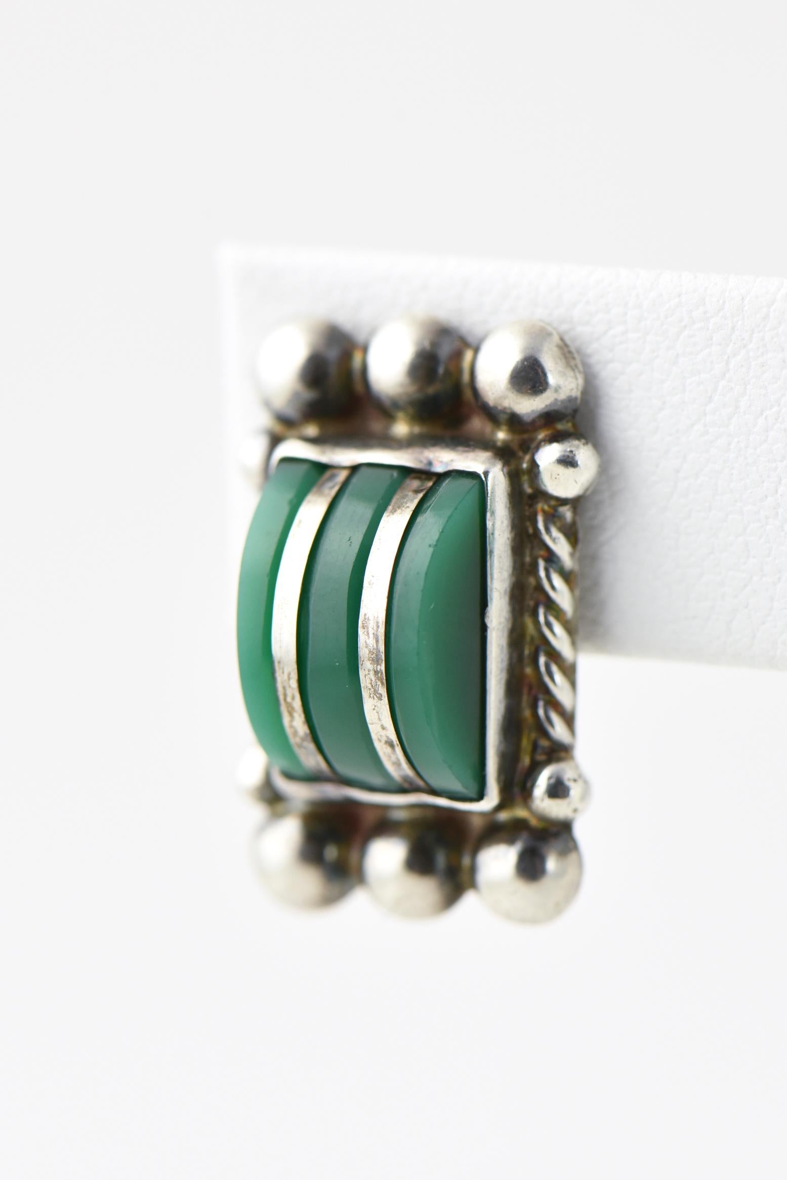 Sterling silver and green onyx inlay earrings designed by a Mexican artist. The outer sides have a coiled column with large sterling orbs at the top and bottom edges. Illegibly signed, possibly Jiaz Santov. Screws back. Age wear.
