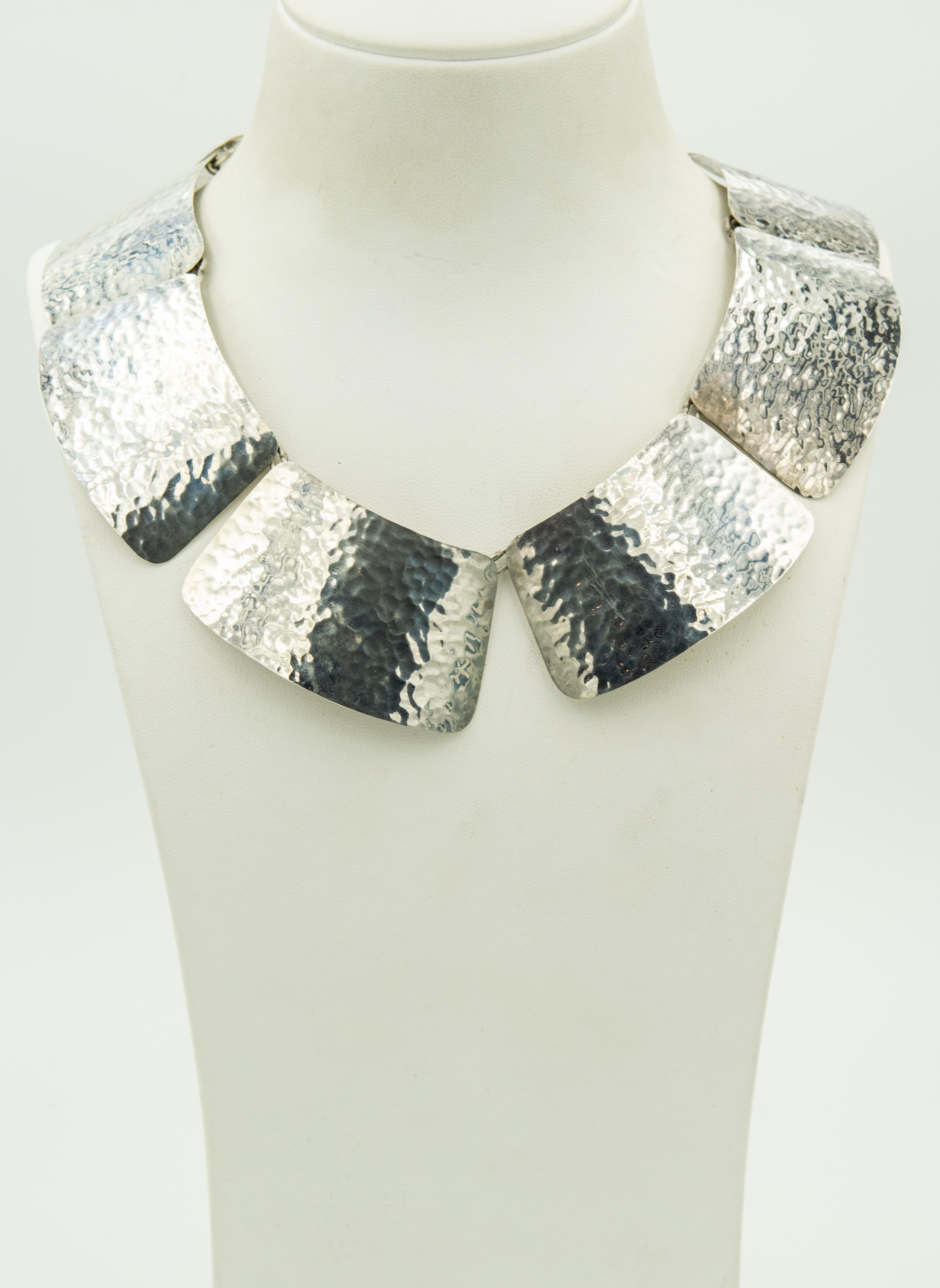 This beautiful modernist necklace was made in Mexico in the mid 20th Century.  
It features 8 hammered sterling silver slightly curved trapezoids which are linked together at the the top corners. The trapezoids measure 1.72