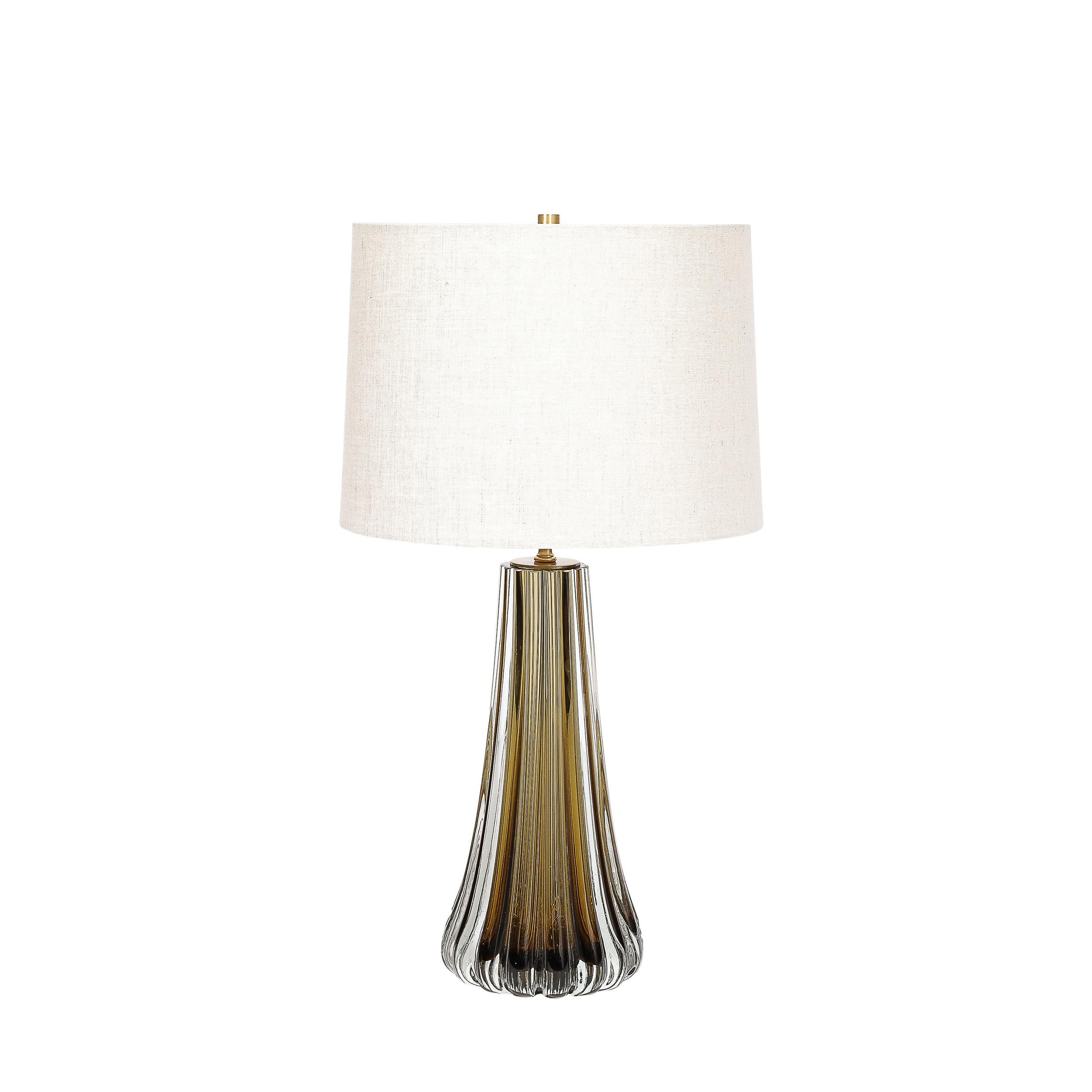 This exquisitely elegant Pair of Modernist Hand-Blown Murano Glass Table Lamps in Smoked Topaz W/ Stylized Fluted Detailing originate from Italy during the 21st Century. The lamps feature bodies formed in Hand-Blown Murano glass in a beautiful