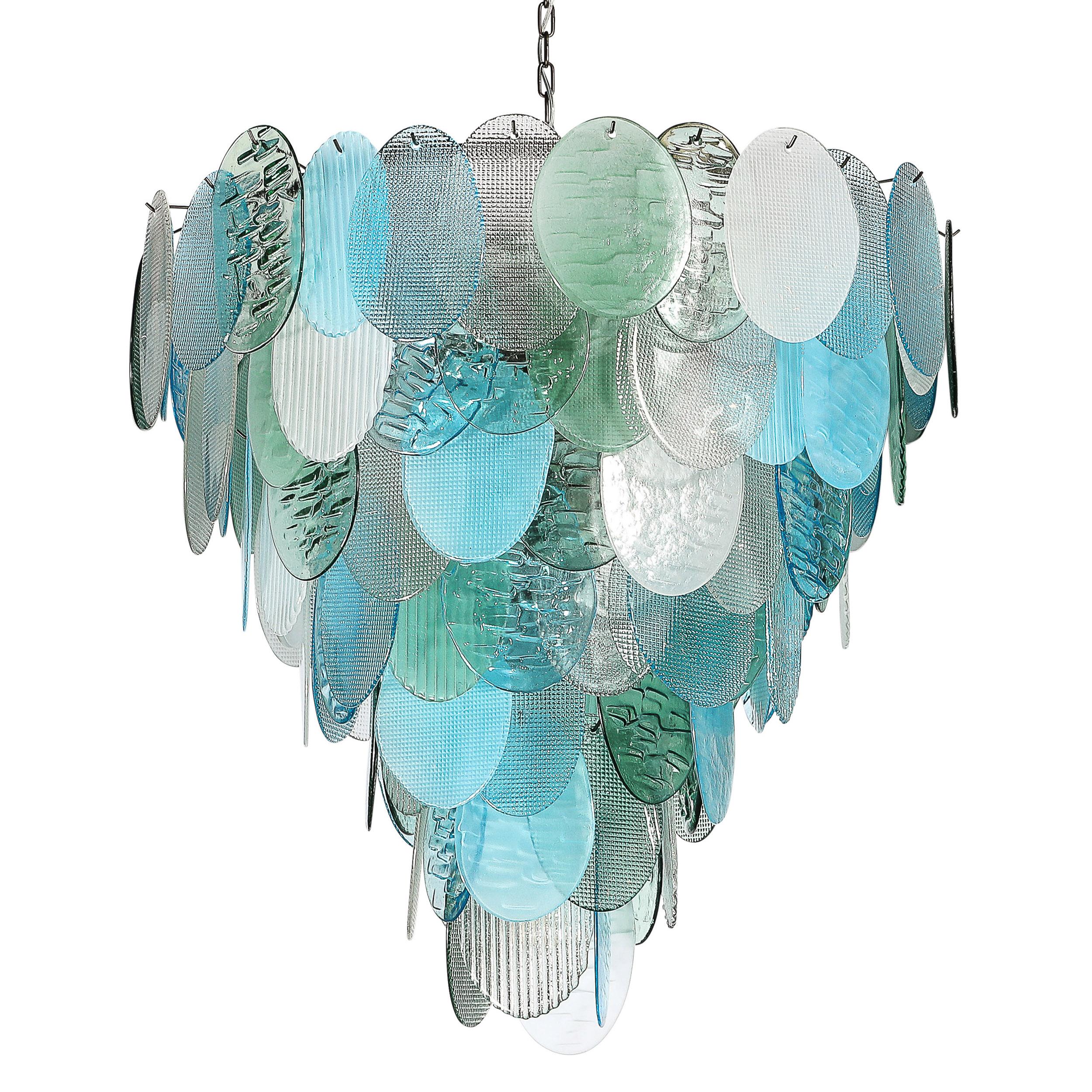 Ce lustre saisissant présente sept niveaux de disques en verre de Murano soufflés à la main, chacun étant façonné avec une variété de finitions texturales complexes. Certains disques présentent des indentations qui rappellent la pression d'une pelle