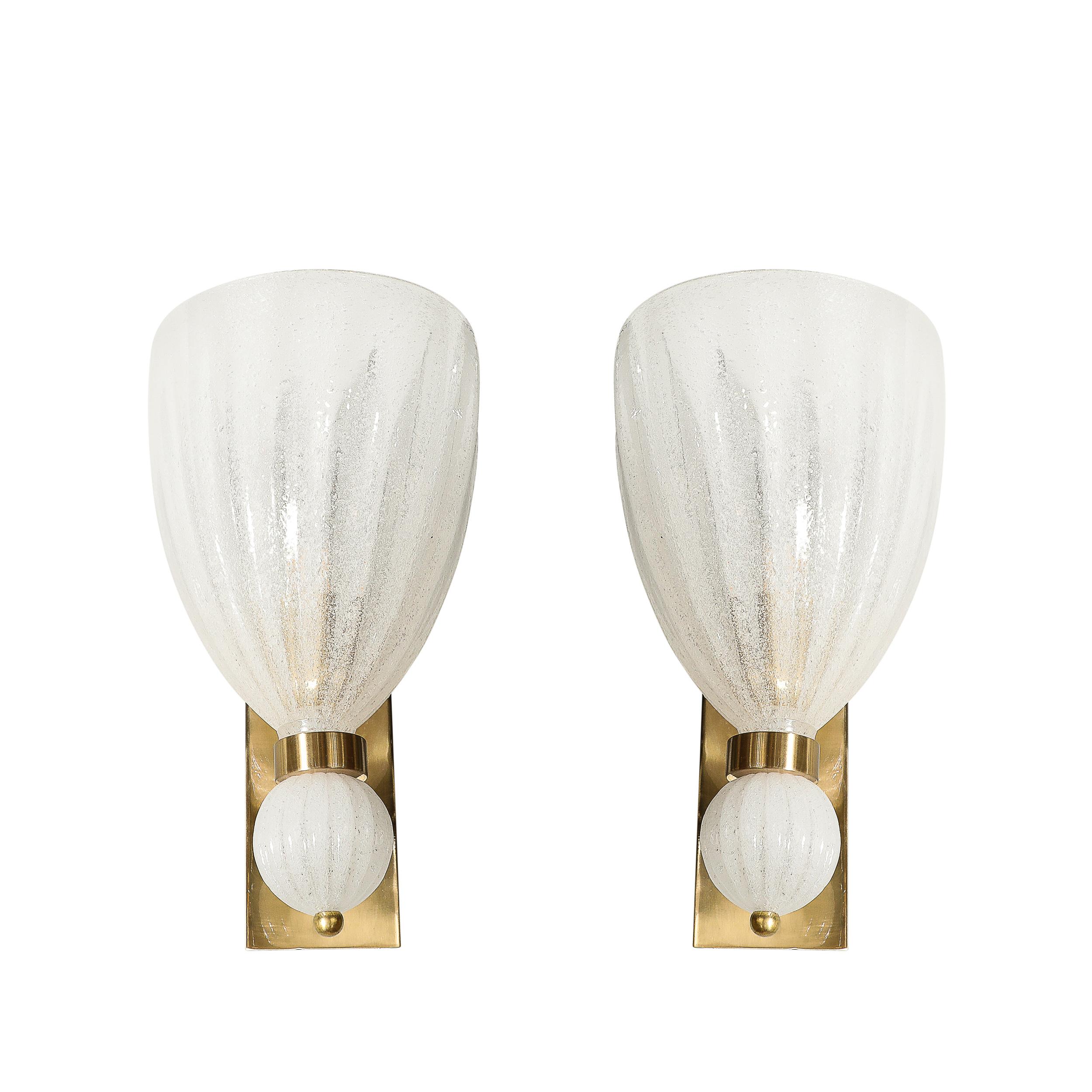 Questa elegante coppia di scensori modernisti in vetro di Murano soffiato a mano e scanalato, con goccia orbitale e raccordi in ottone, proviene dall'Italia del XXI secolo. Presentano una forma classica abbracciata da un raccordo circolare in ottone