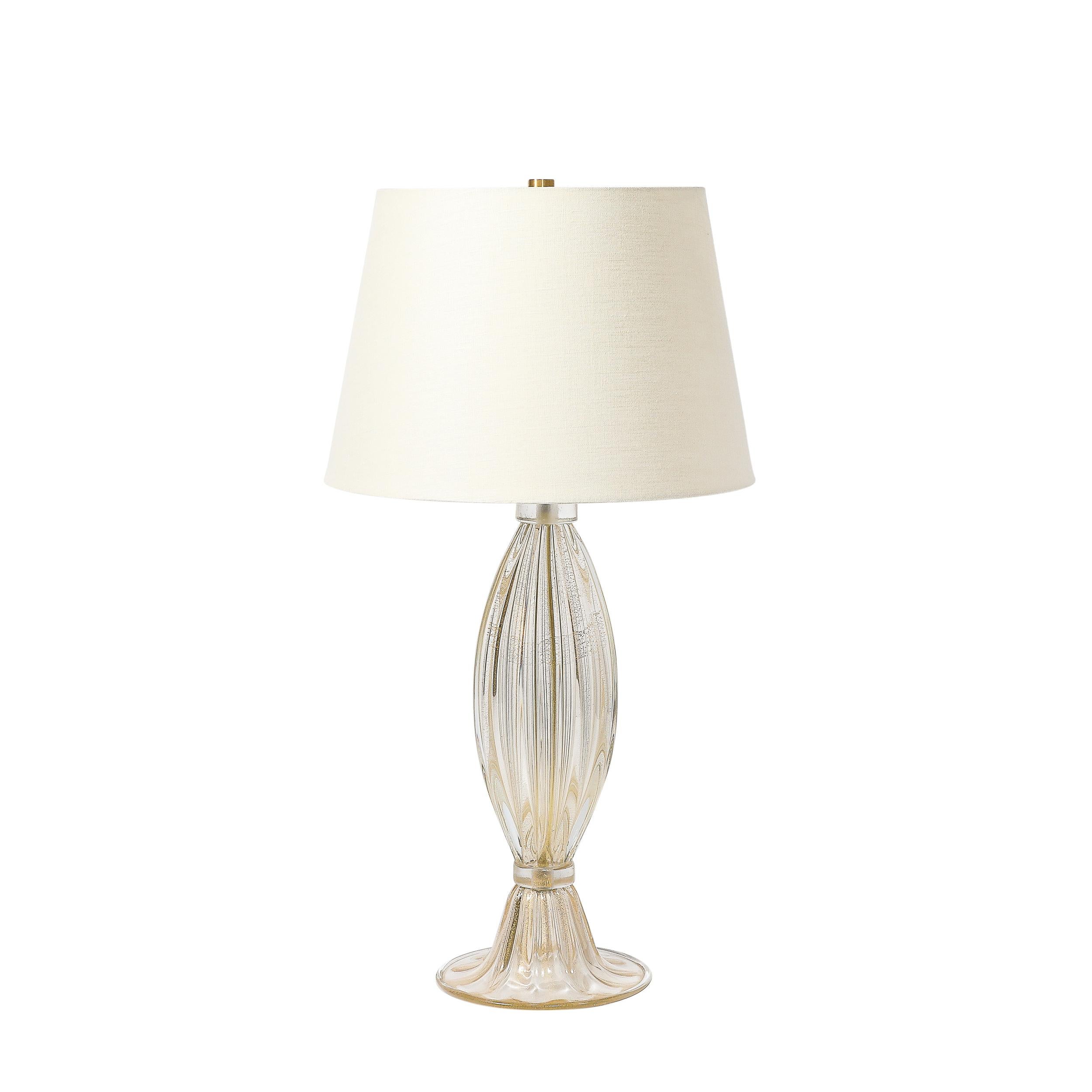 This exquisitely elegant Pair of Modernist Hand-Blown Transparent & Fluted Murano Glass Table Lamps W/ 24Karat Gold Fleck Detailing originates from Italy during the 21st Century. They feature bodies rendered in the highest quality hand-blown murano