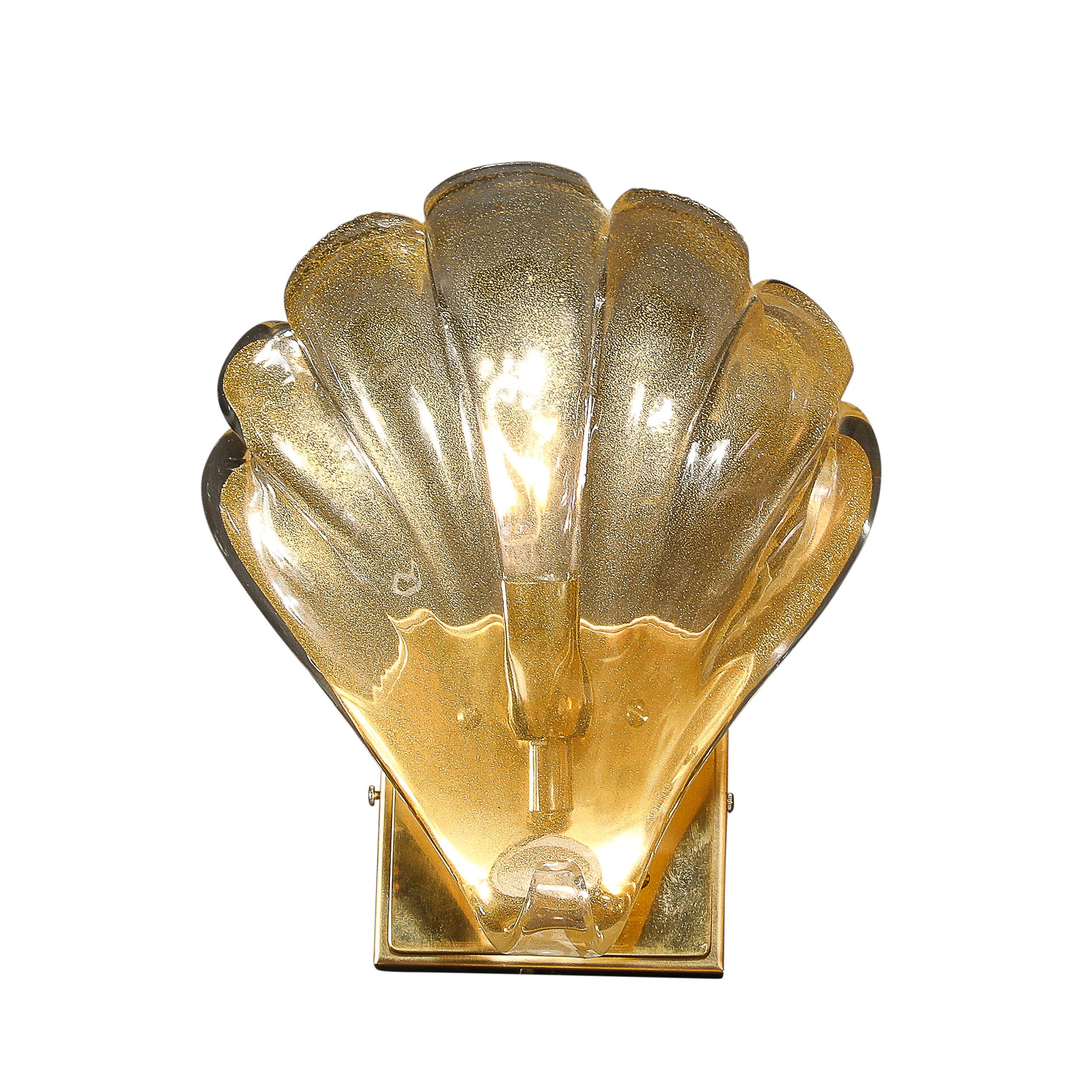 This lovely Pair of Modernist Hand-blown Murano Glass Shell Form Sconces W/ 24 Karat Gold Flecks and Brass Fittings originates from Italy during the 21st Century. They feature minimal shades with fluted detailing and a scalloped top edge rendered in