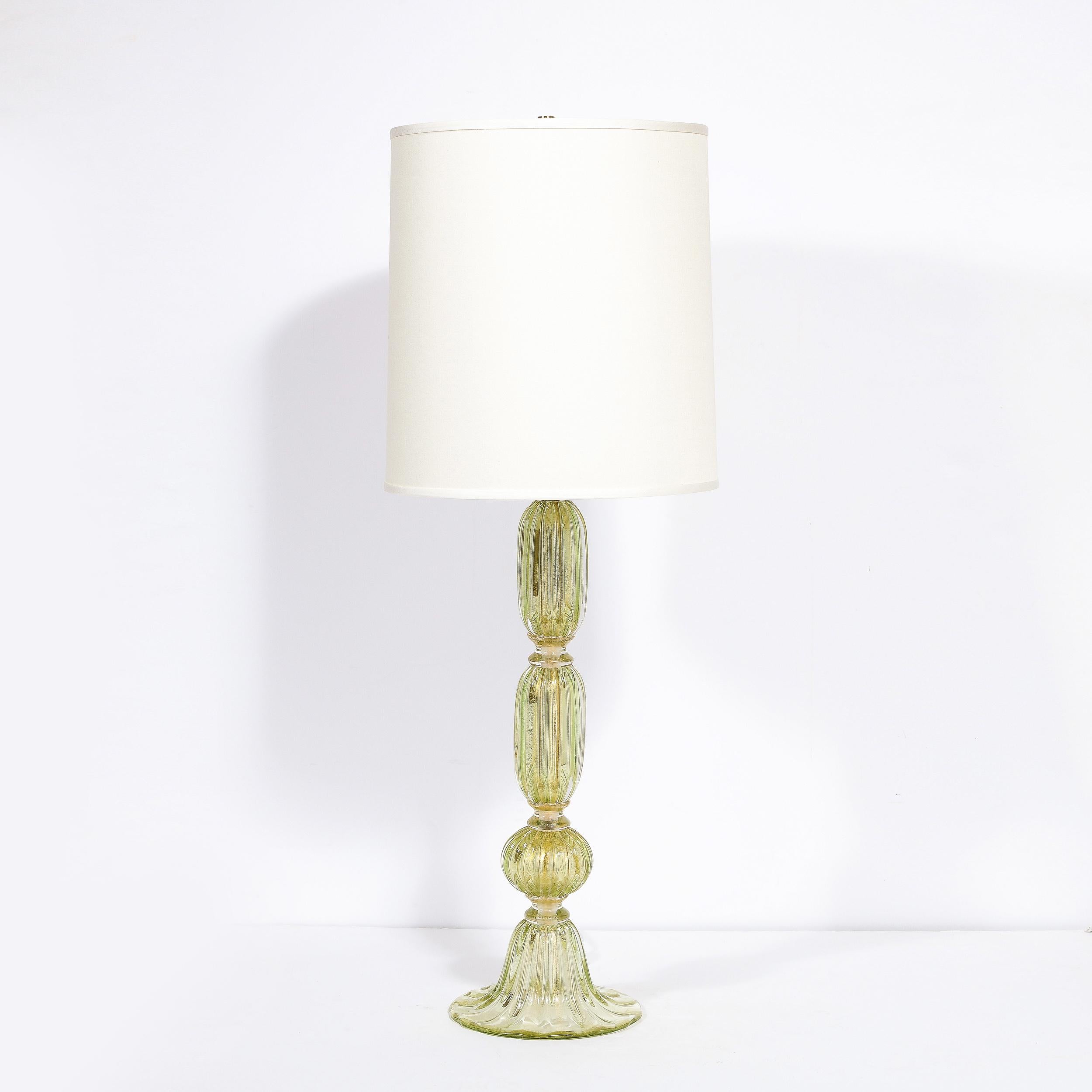This dramatic and elegant table lamp was handblown in Murano, Italy- the island off the coast of Venice renowned for centuries for its superlative glass production. It features a sculptural undulating cylindrical body in handblown translucent reeded