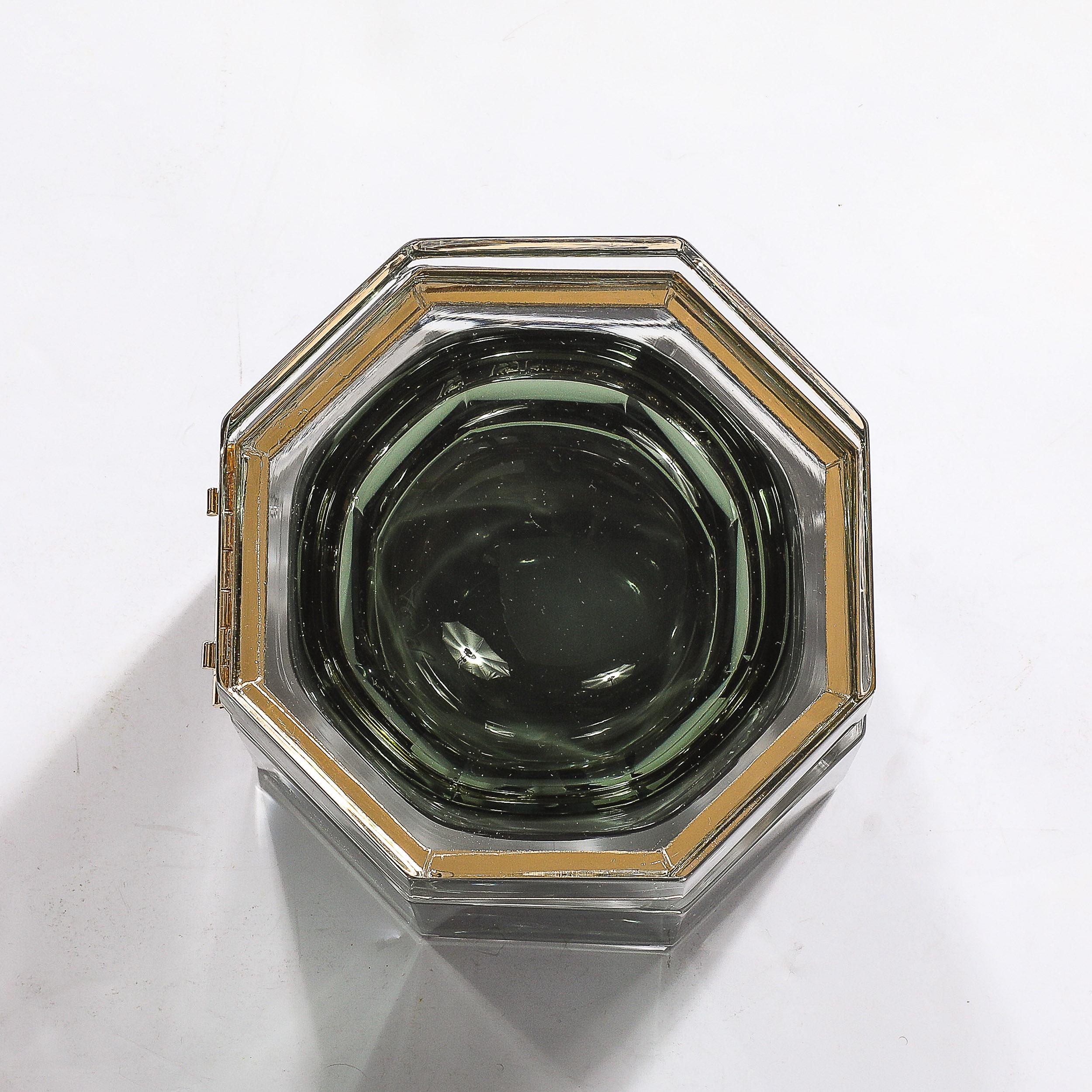 This beautifully colored and elegant Modernist Hand-Blown Murano Octagonal Glass Box in Emerald W/Brass Fittings originates from Italy during the 21st Century. Features an octagonal profile rendered in hand-blown murano glass, transparent along the
