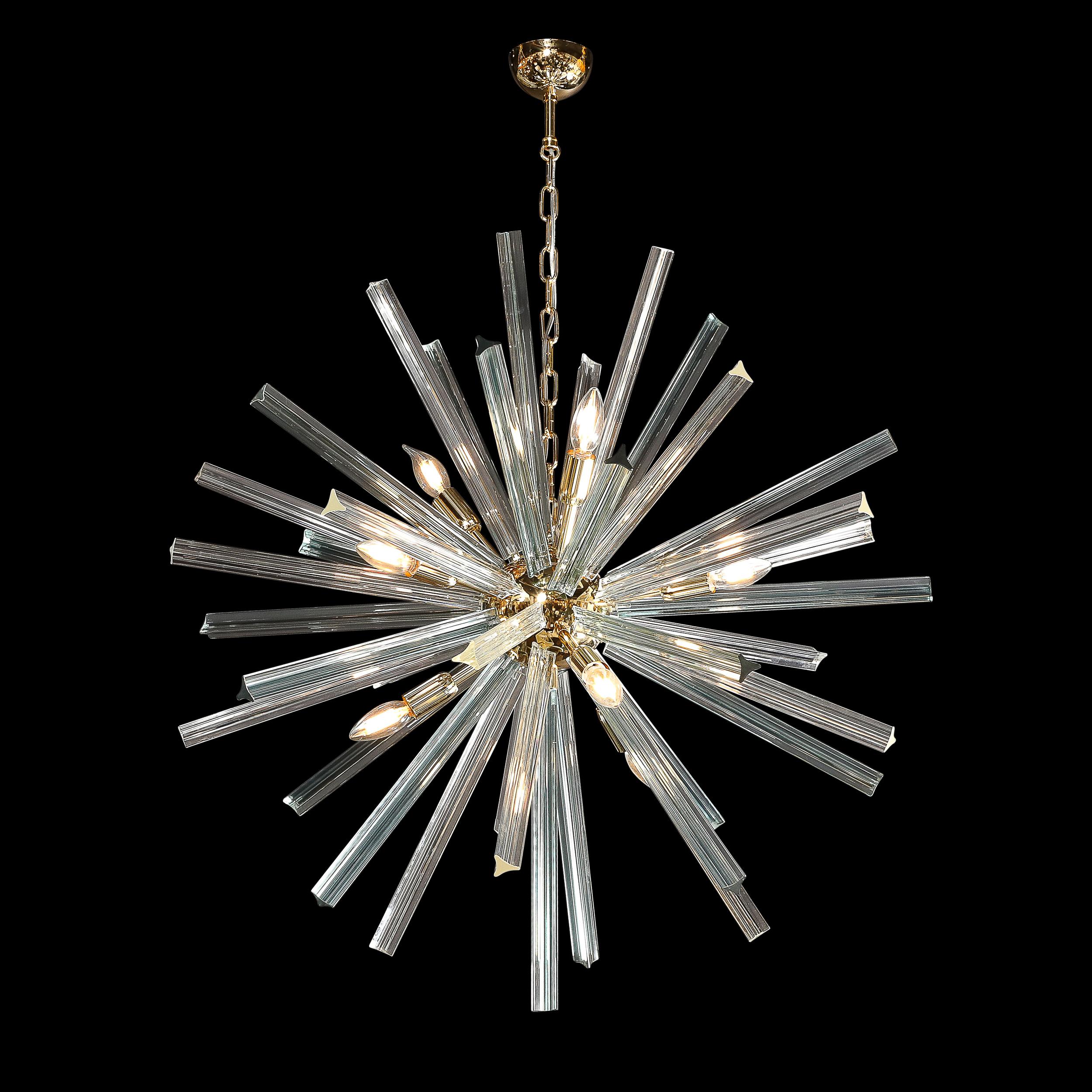 Esta impresionante araña Sputnik de cristal de Murano soplado a mano, de color aguamarina ahumado, procede de Italia y data del siglo XXI. Esta luminaria está llena de energía, con un elemento esférico de latón pulido al que se adhiere el cristal y
