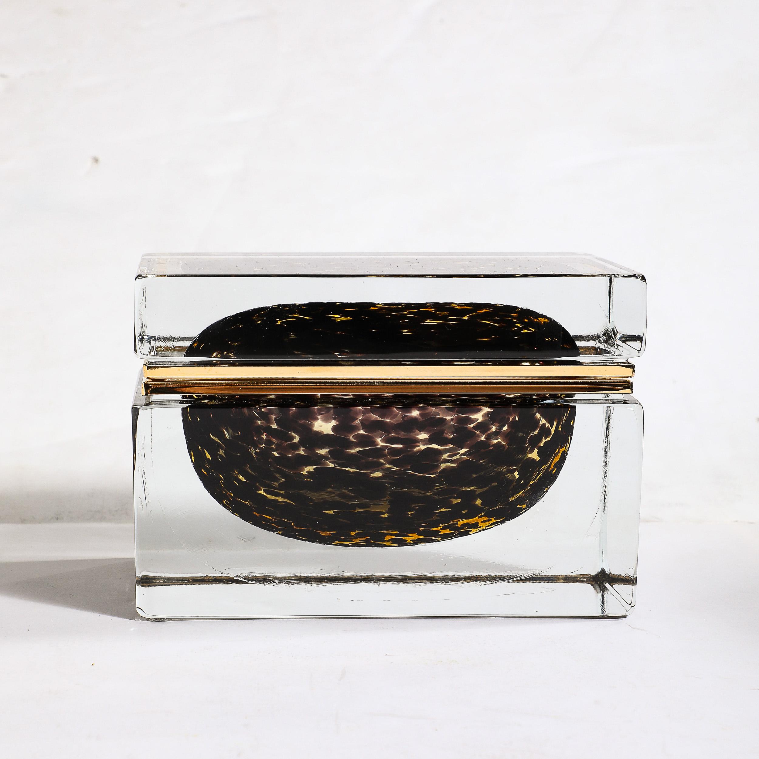 This chic and sophisticated Modernist Hand-Blown Murano Glass Box in Spotted Jet Black & Clear Glass W/Brass Fittings originates from Italy during the 21st Century. Features a rectilinear composition with transparent glass on the exterior of the