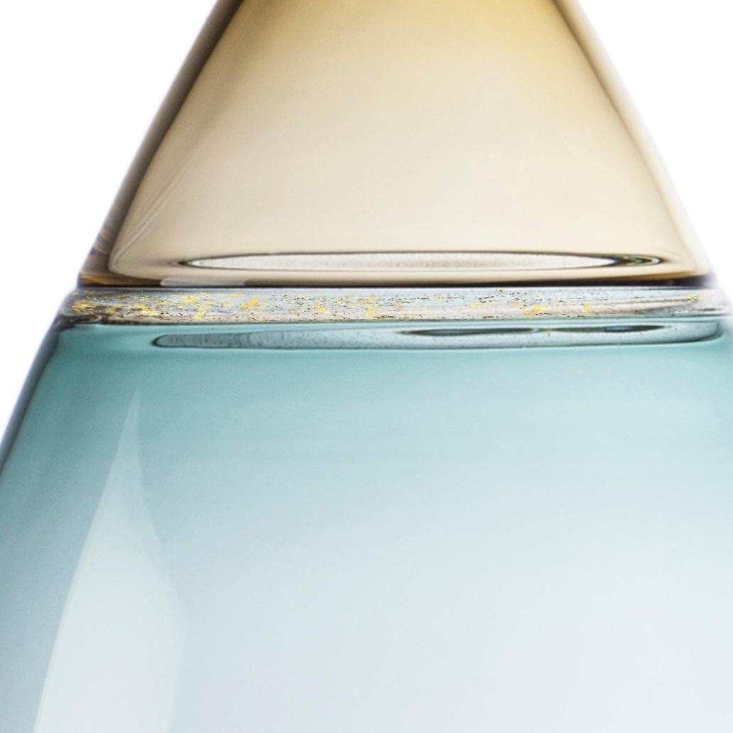 Voluminous, two-toned hand blown glass statement vessel features pale amber straw and blue-green tourmaline translucent hues. A speckled gold leaf seam emphasizes the shoulder. The Goccia (Italian: 
