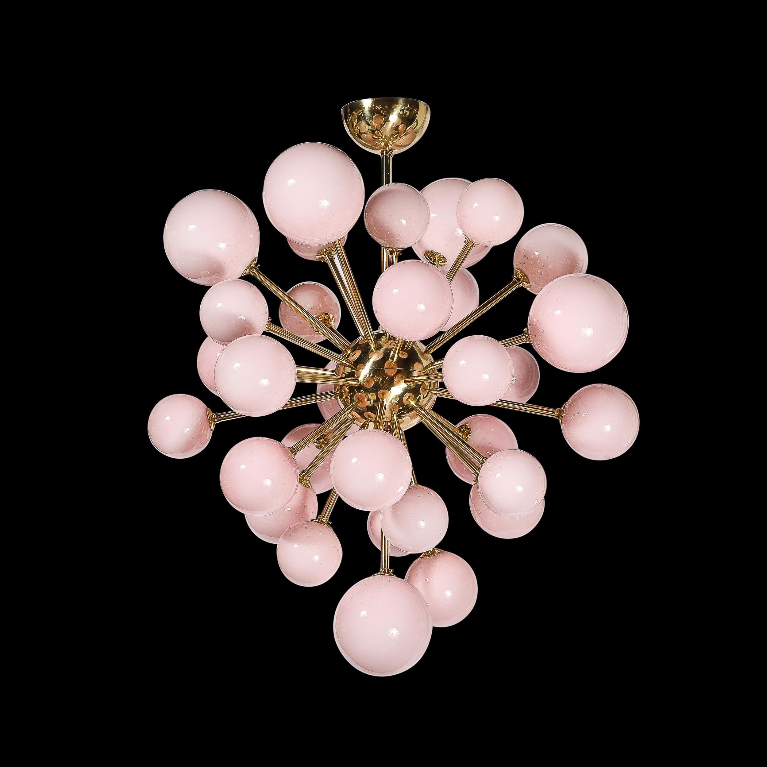Questo elegante ed equilibrato lampadario modernista Sputnik in vetro di Murano soffiato a mano con paralumi rosa smerigliati e accessori in ottone proviene dall'Italia del XXI secolo. Presenta una forma a Sputnik con un centro sferico in ottone da