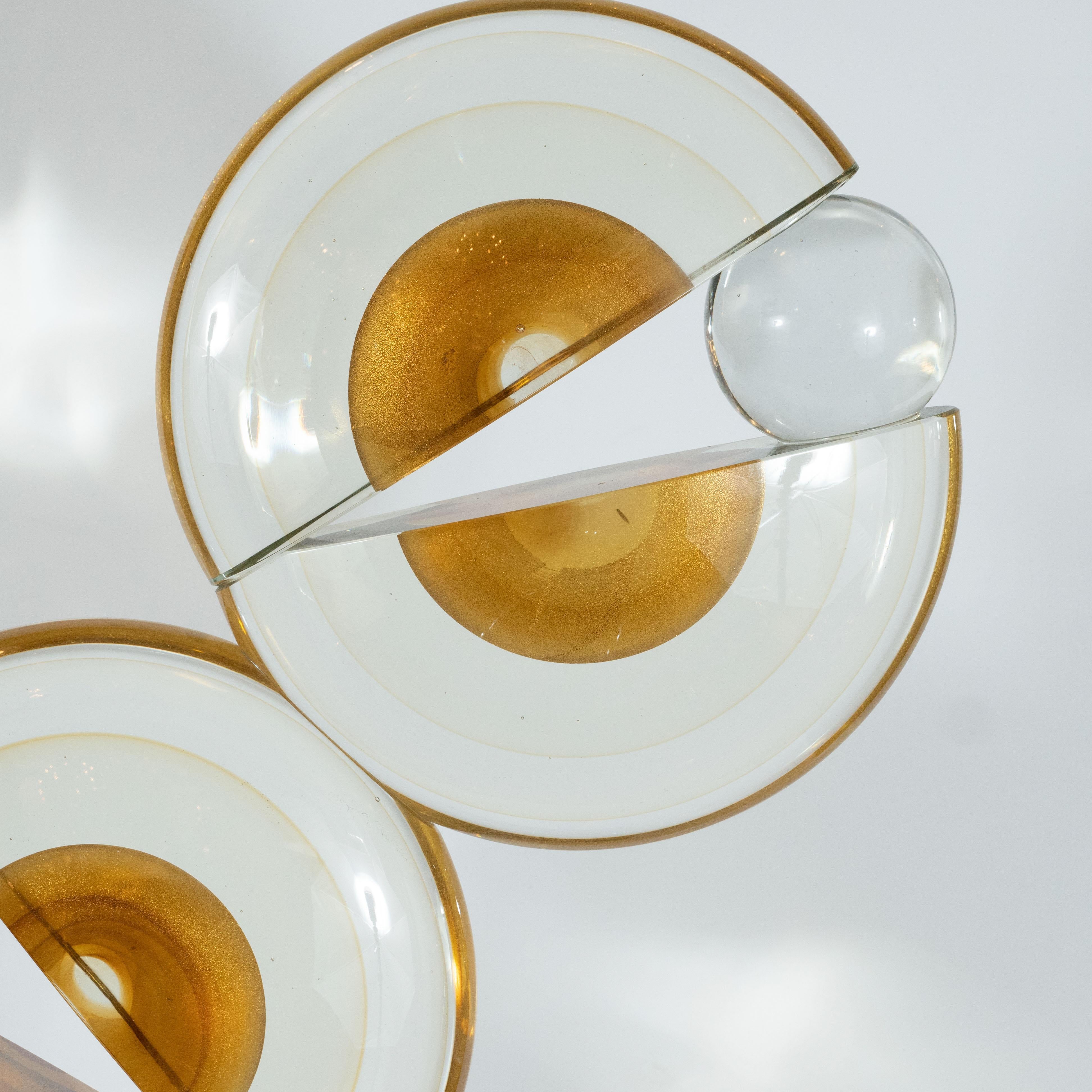 This dynamic modernist sculpture was hand blown in Murano, Italy- the island off the coast of Venice renowned for centuries for its superlative glass production. It features three spherical forms with circular embellishments in 24-karat gold, split