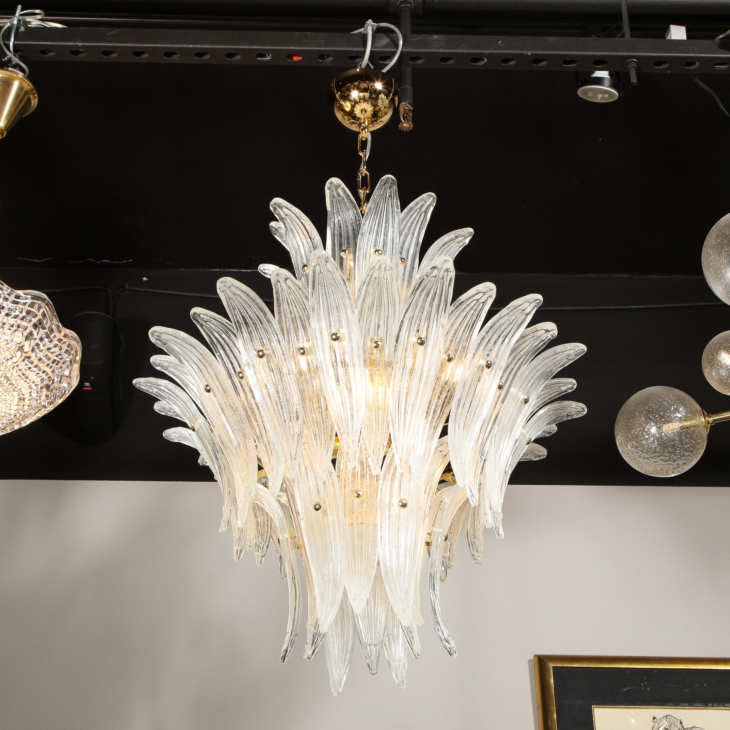 This sophisticated modernist glass chandelier was realized in Murano, Italy- the island off the coast of Venice renowned for centuries for its superlative glass production. It features a body reminiscent of palm leaves and a brass interior that