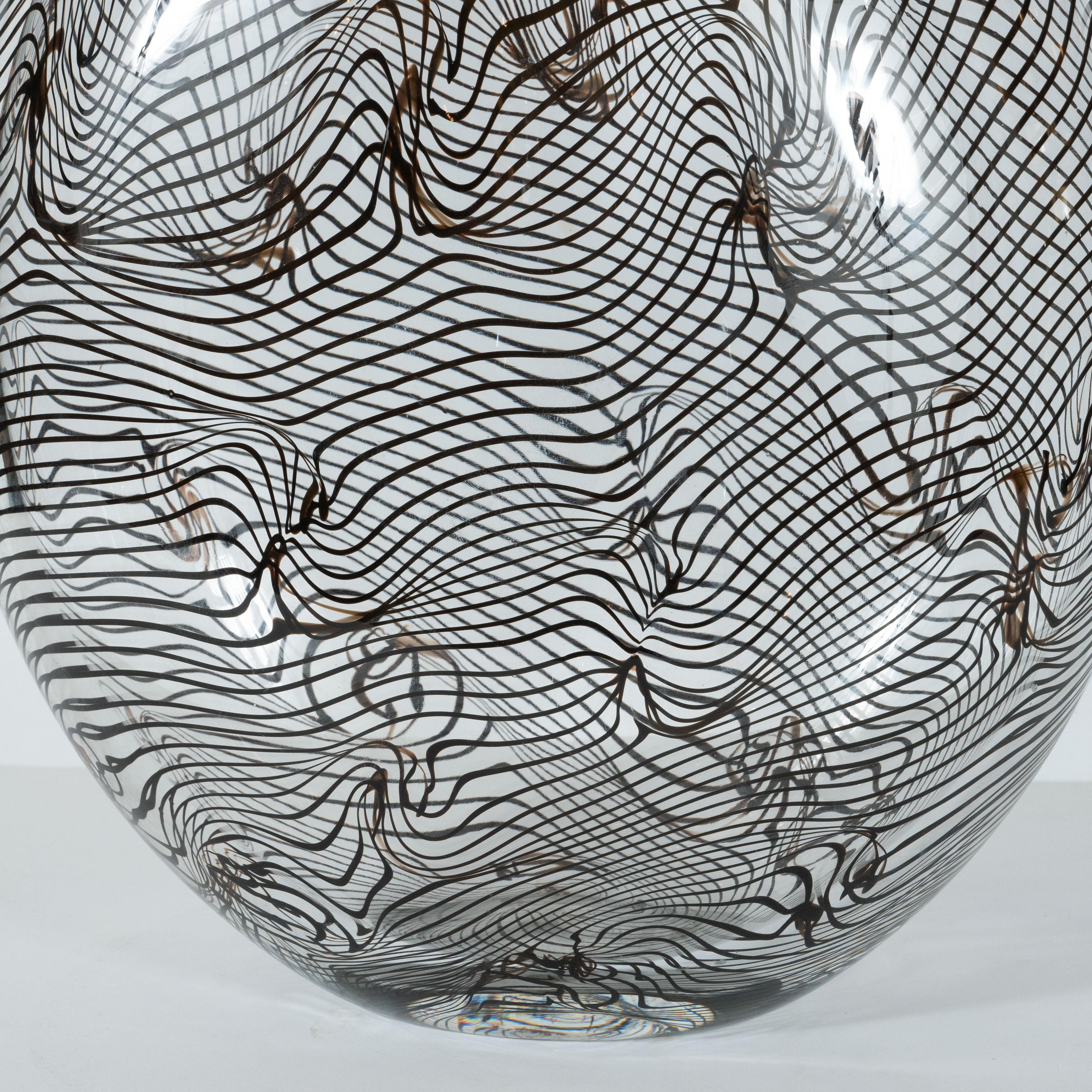 This stunning vase was hand blown in Murano, Italy- the island off the coast of Venice renowned for centuries for its superlative glass production. It features a tear drop form body with a slender conical neck and a circular mouth hand blown in