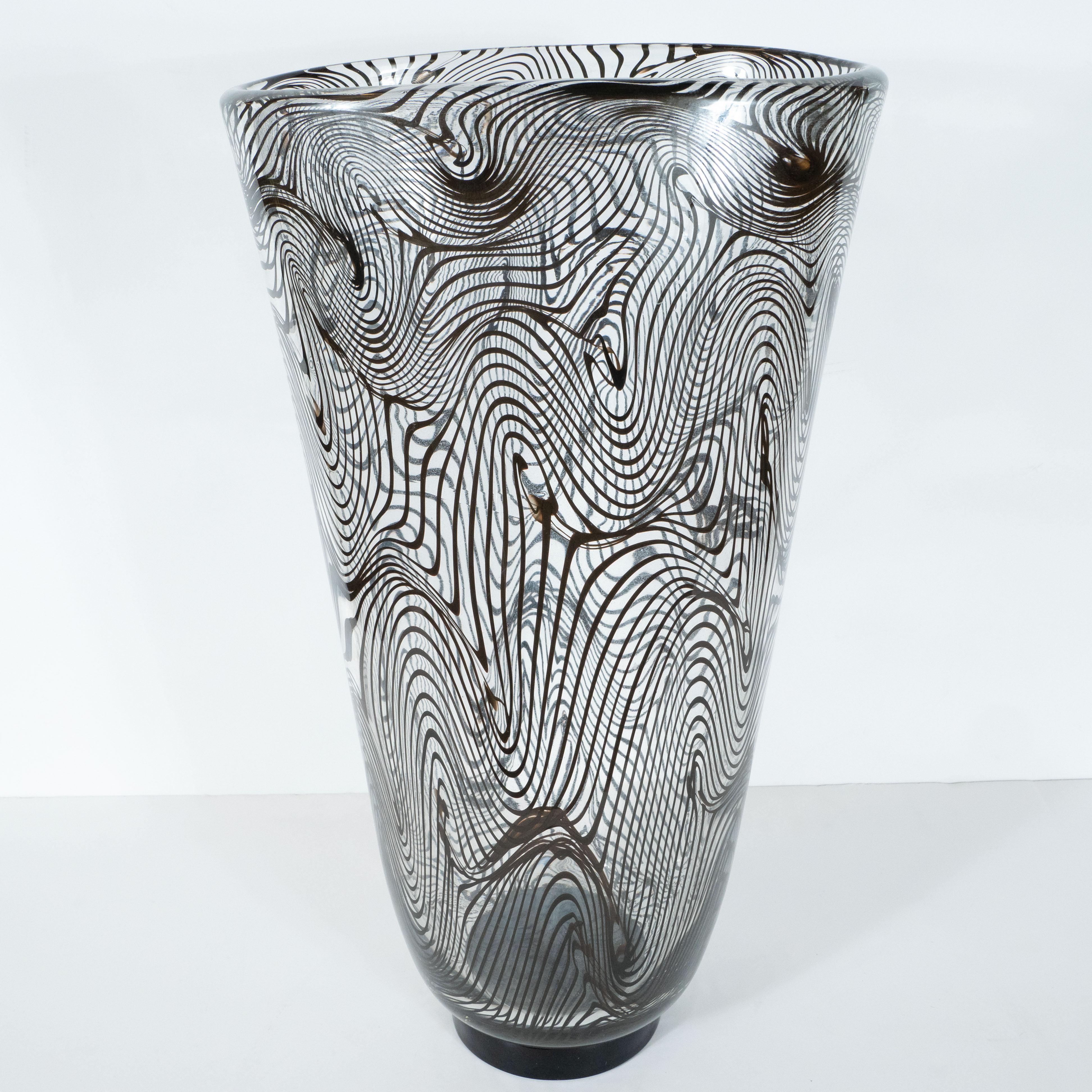 This stunning vase was hand blown in Murano, Italy. The island off the coast of Venice renowned for centuries for its superlative glass production. It features a volumetric oblong body in translucent glass with beautiful opaque black swirl detailing