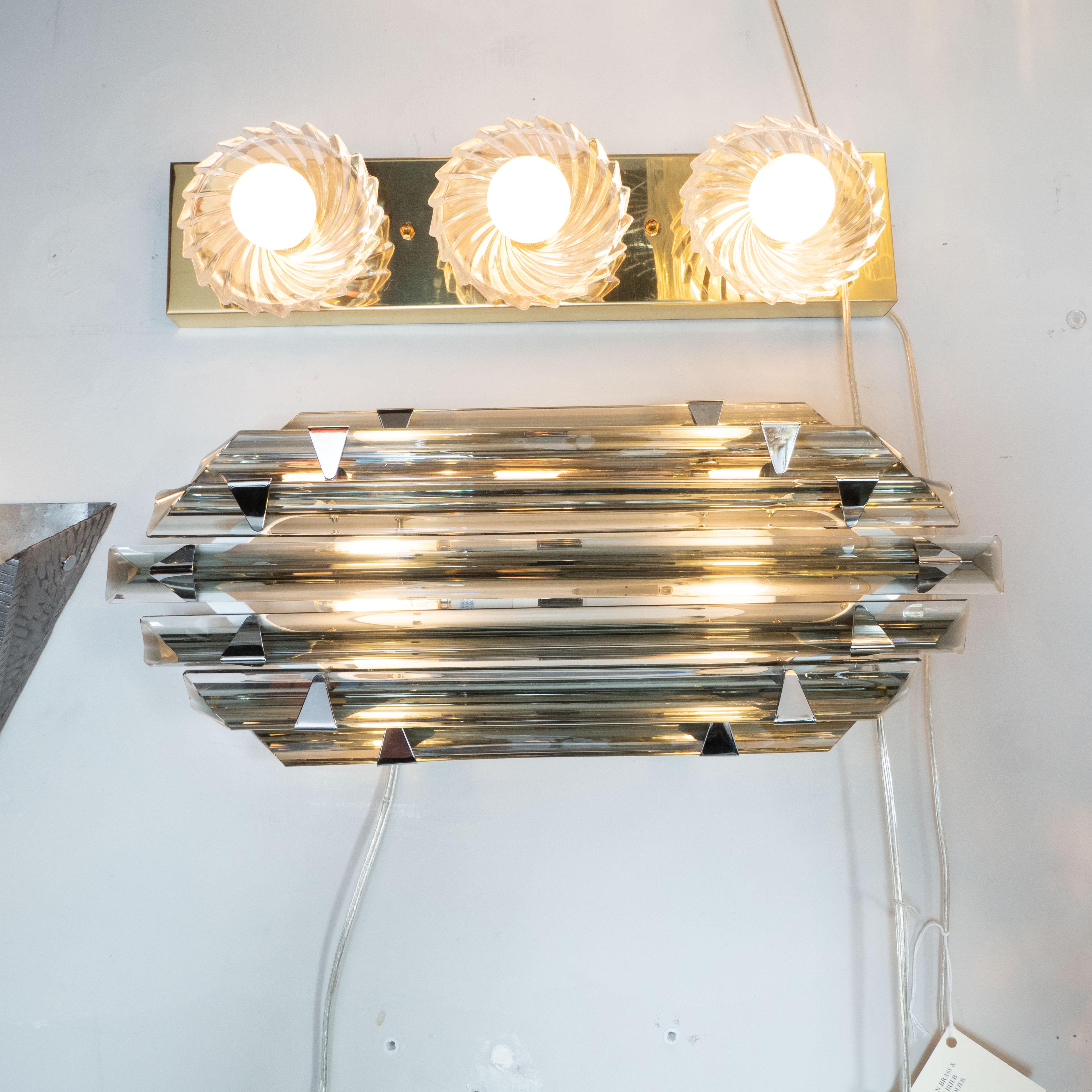This stunning modernist vanity light/ sconce was realized in Murano, Italy- the island off the coast of Venice renowned for centuries for its superlative glass production. It features hand blown smoked Murano subtly convex glass rods of staggered