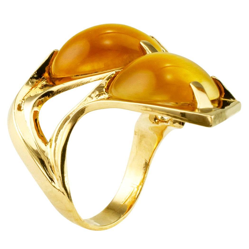 Modernist 1970s honey colored tiger eye and gold ring. The avant garde design is composed by broad ribbons of 14-karat gold that curve and sweep graciously over the top of the finger to showcase a pair of honey colored tiger eye cabochons. A ring