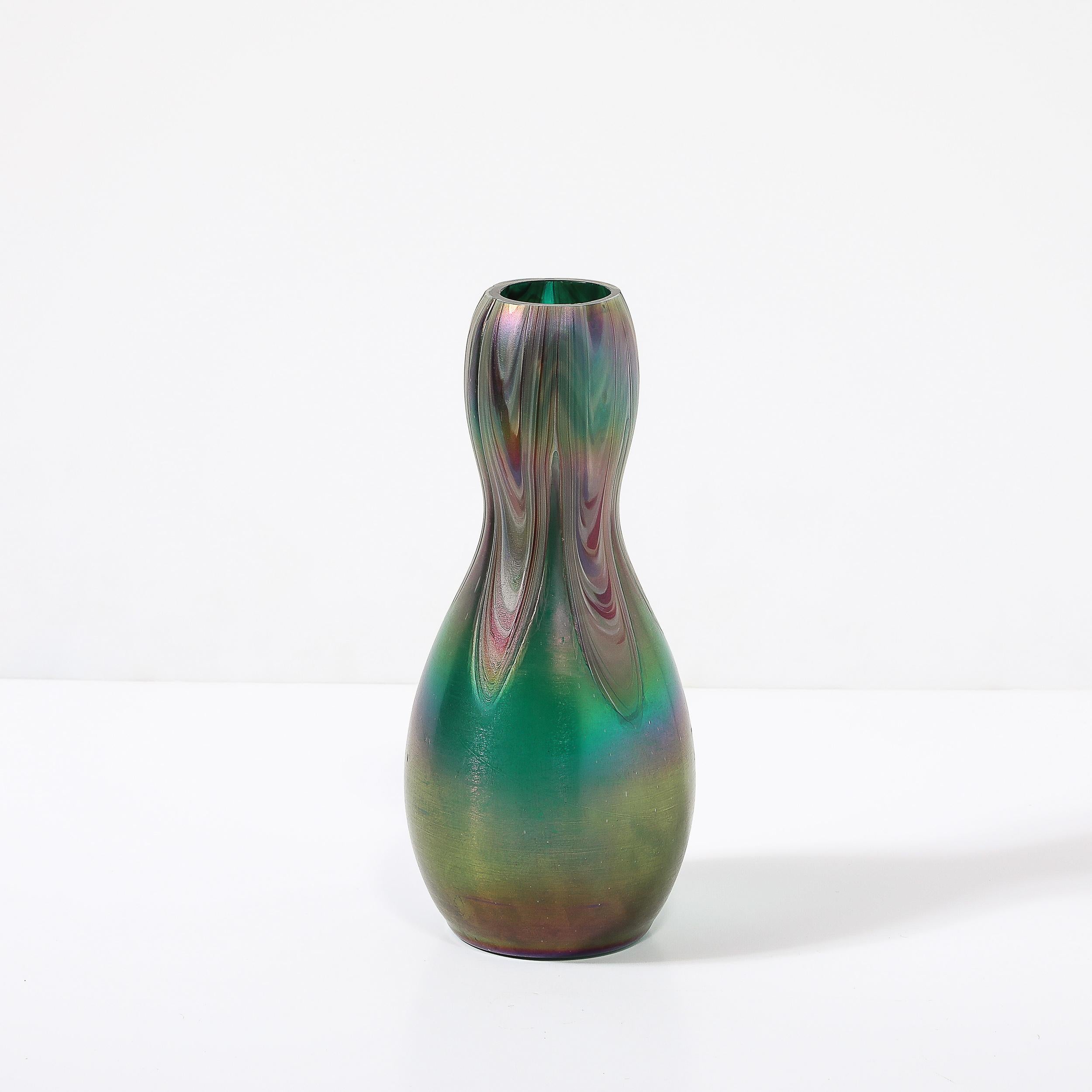 Questo dinamico e materialmente intrigante vaso di vetro artistico modernista a forma di clessidra con volute di Favrile proviene dagli Stati Uniti del XX secolo. Presenta una superficie incredibilmente dettagliata di vetro artistico favrile
