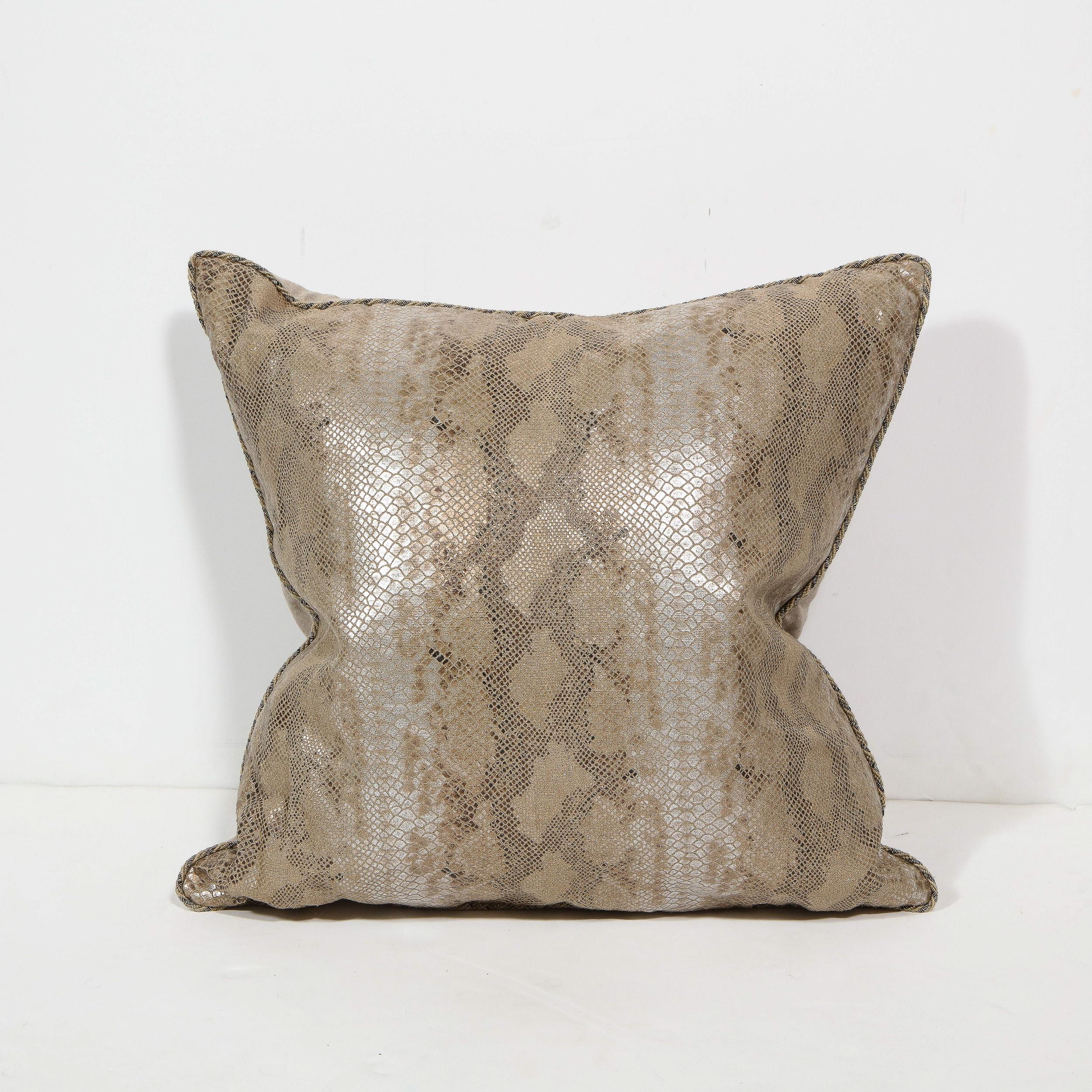 Handcrafted in the United States by Elizabeth Dow home, this bold and sophisticated modernist pillow offers a stylized python print pattern rendered in metallic hues of bronze and silver with undertones of java against a tan background. The pillow