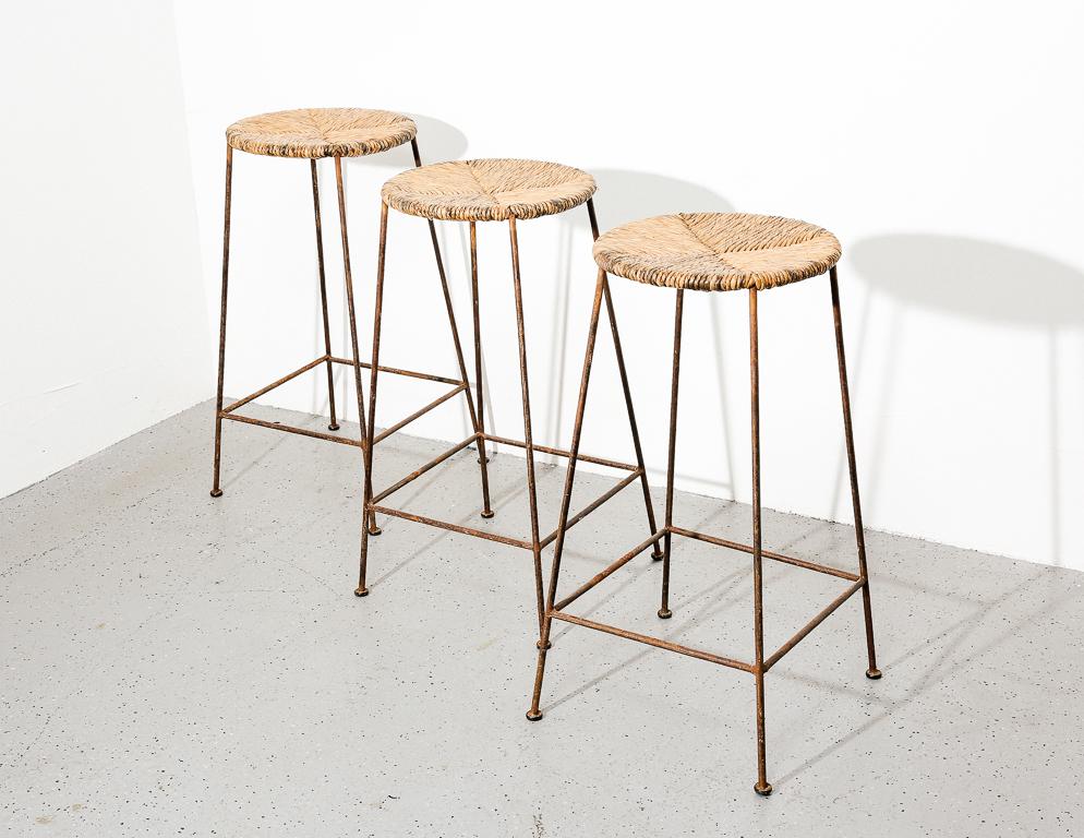 Vintage bar stools with iron frames and rush seats.