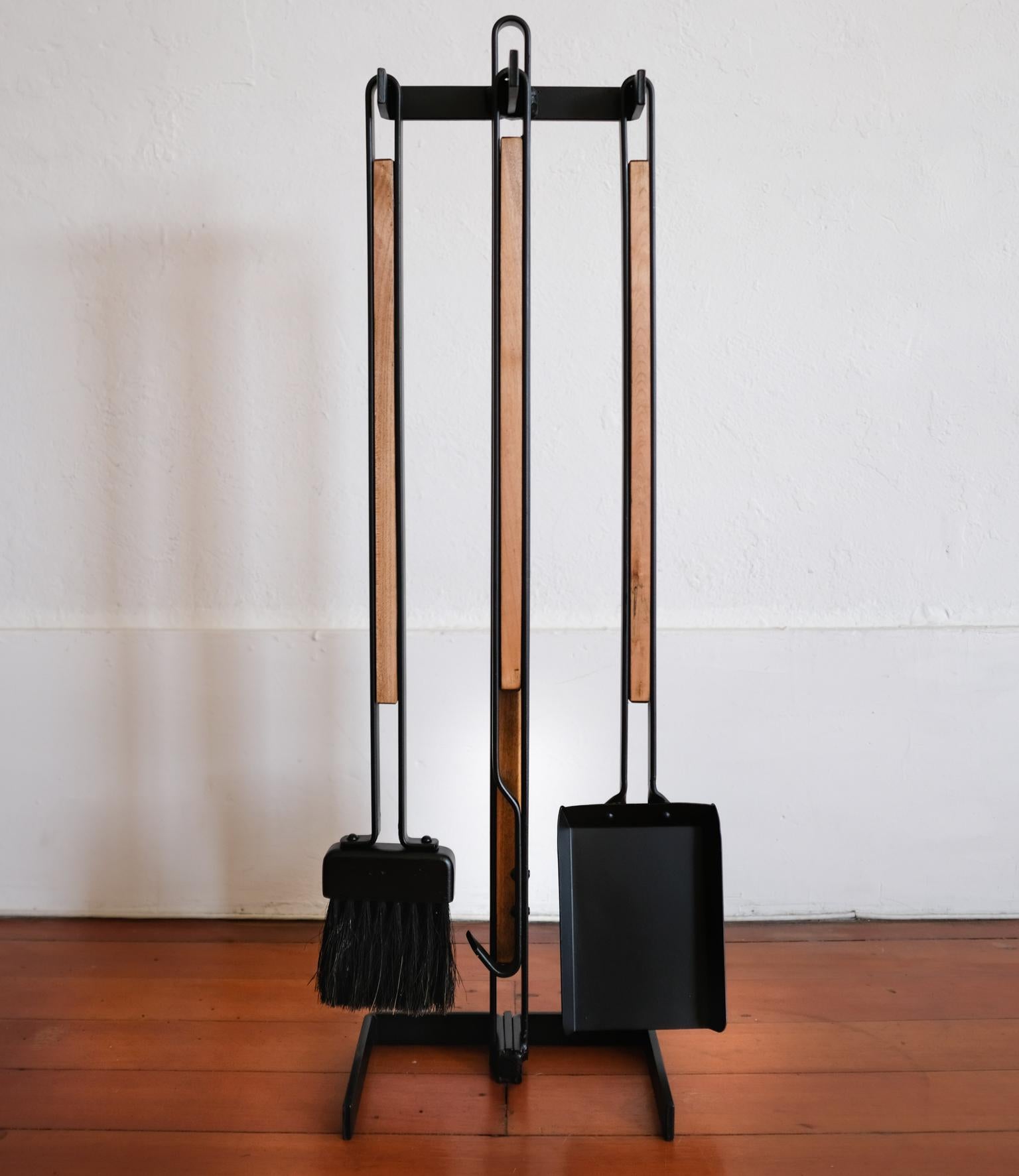 A set of iron fireplace tools with a nice wood detail. Solid construction. It includes the stand, broom poker and shovel, 1960s.