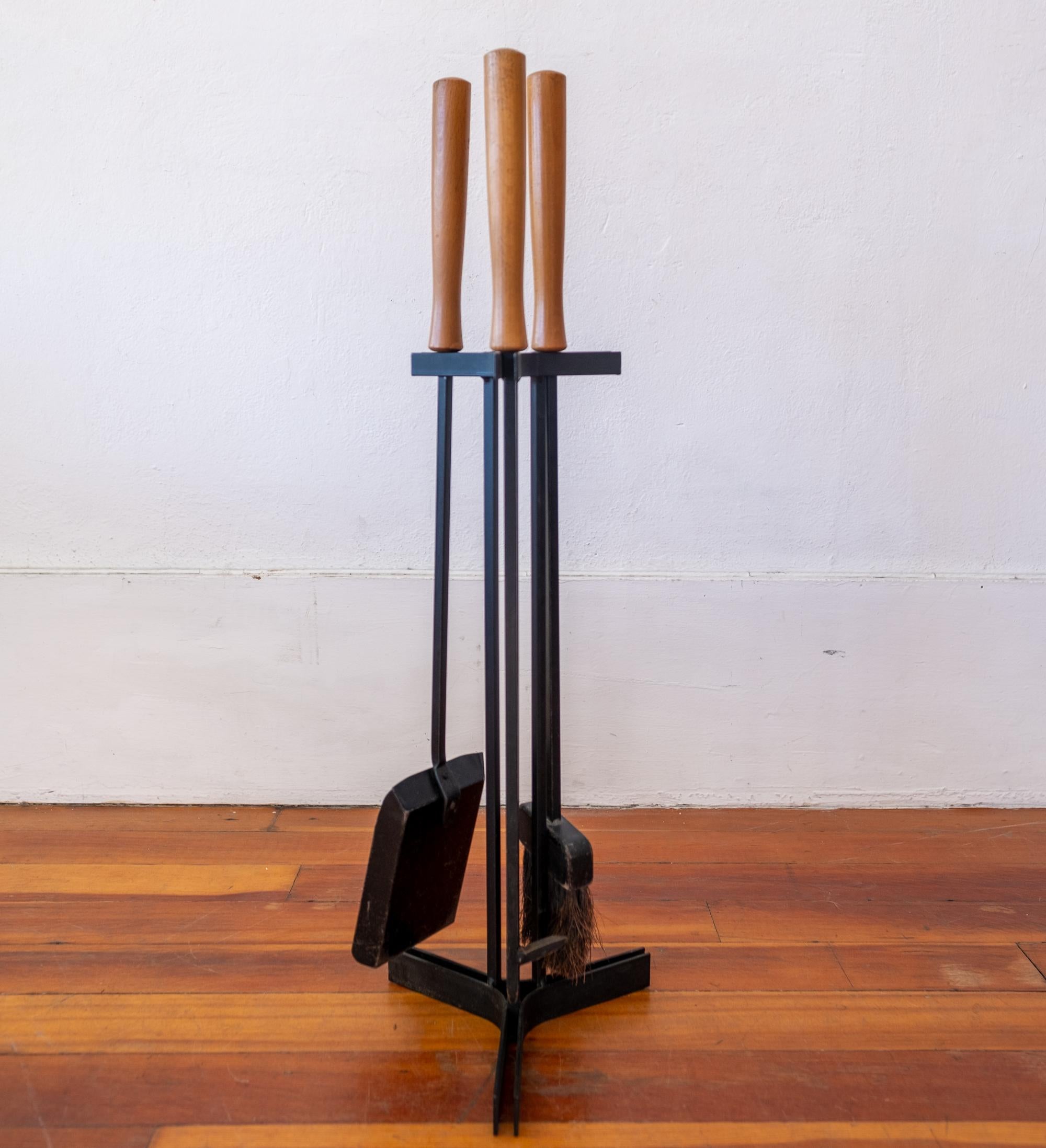 A set of modernist iron fireplace tools with wood handles, 1950s.