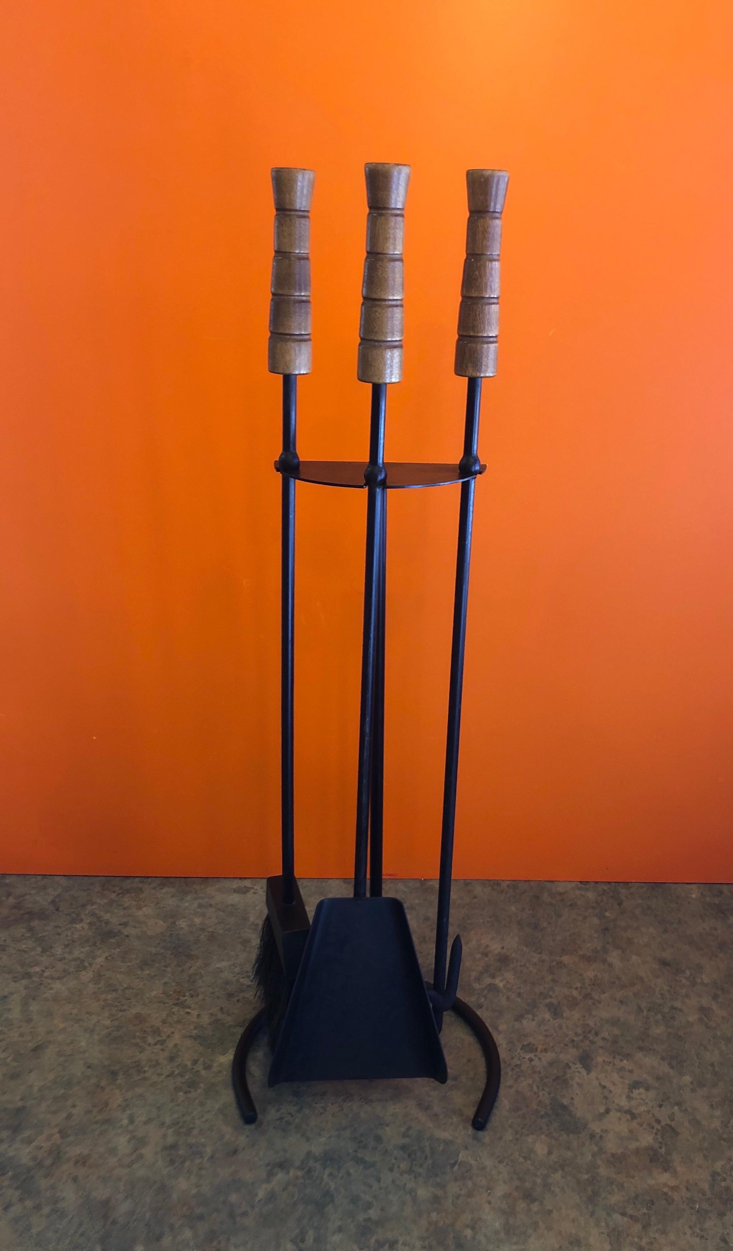 A set of modernist iron fireplace tools with wood handles (pine with walnut stain I beleive), circa 1970s. The set has three 25