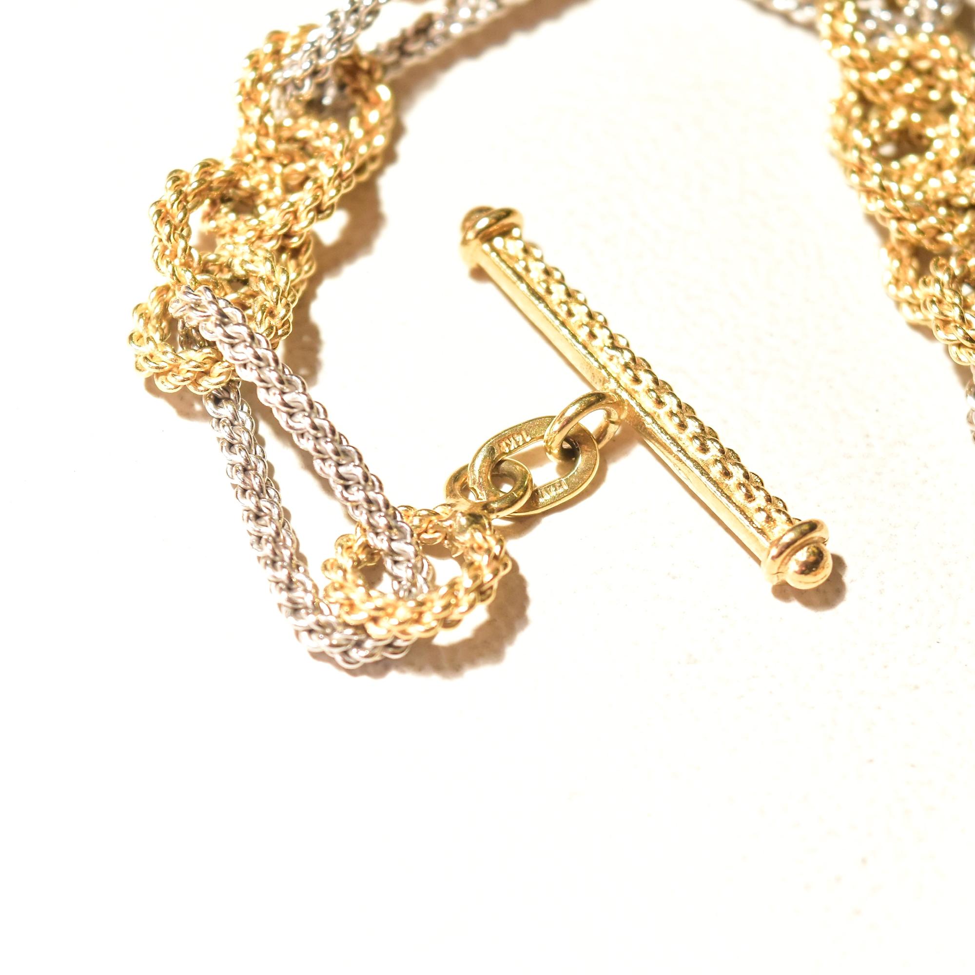An extravagant two-tone 14k gold textured link bracelet for an Italian modernist jewelry collection. Features a figaro style link pattern with round yellow gold links in sets of 4 alternating with long twisted white gold links. The solid gold links