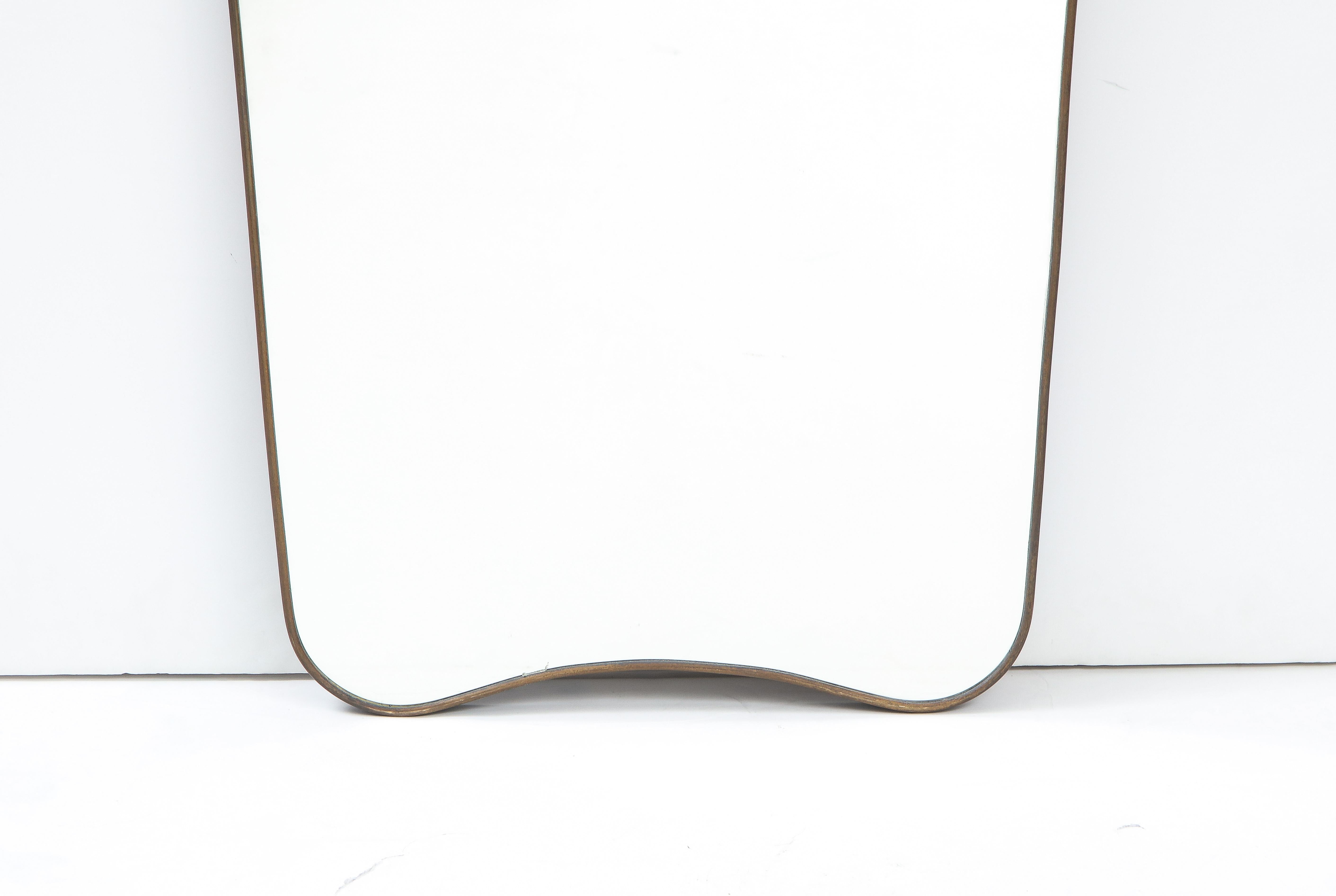 Italian modernist brass elegantly elongated and tapered mirror of grand scale and with beautiful original brass patina. The top has a simple arch, echoed also at the base. This very simple and classic Italian design would complement any interior