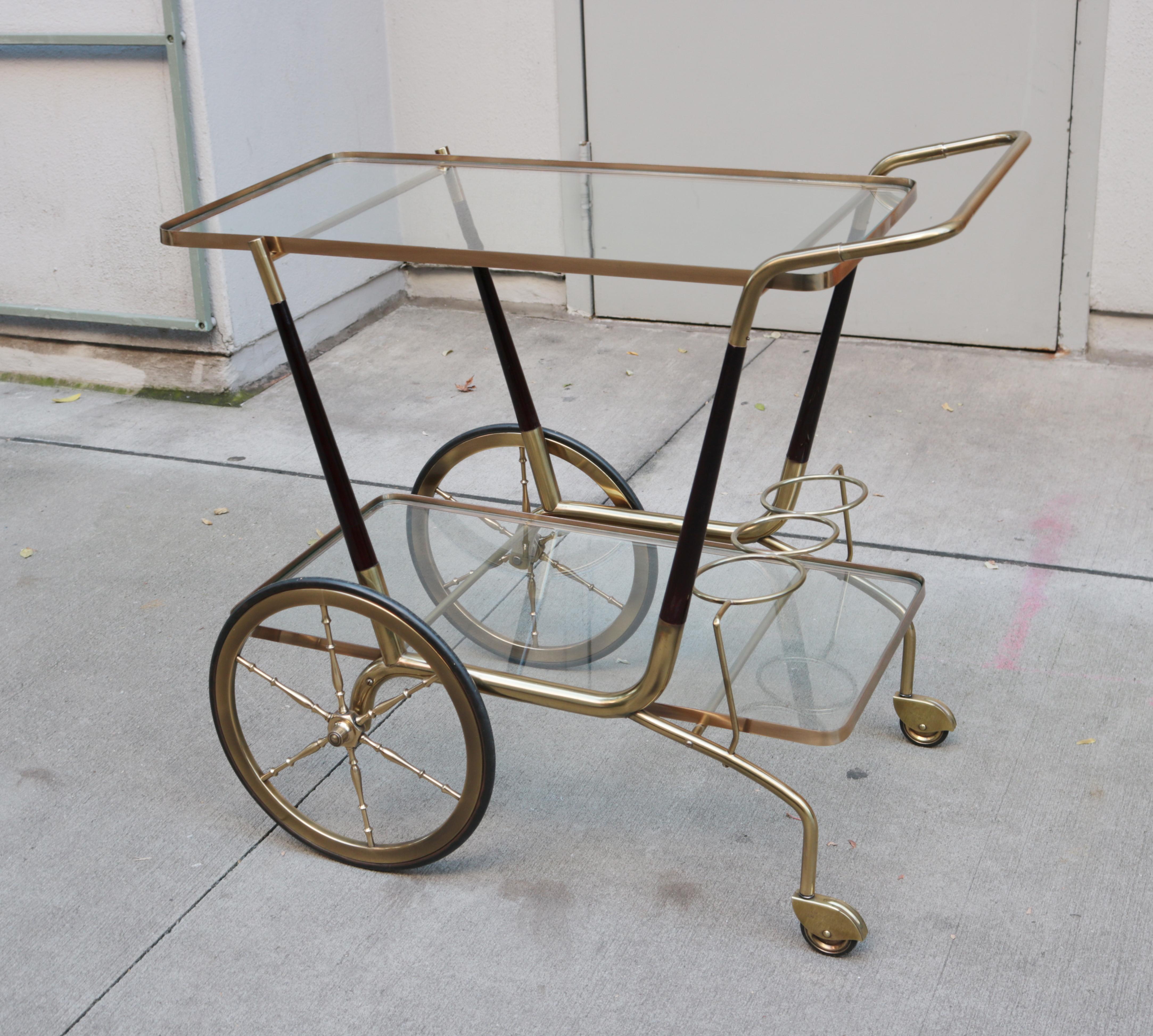 A modernist Italian bar cart. 
Brass with lacquered wood details and two glass shelves.