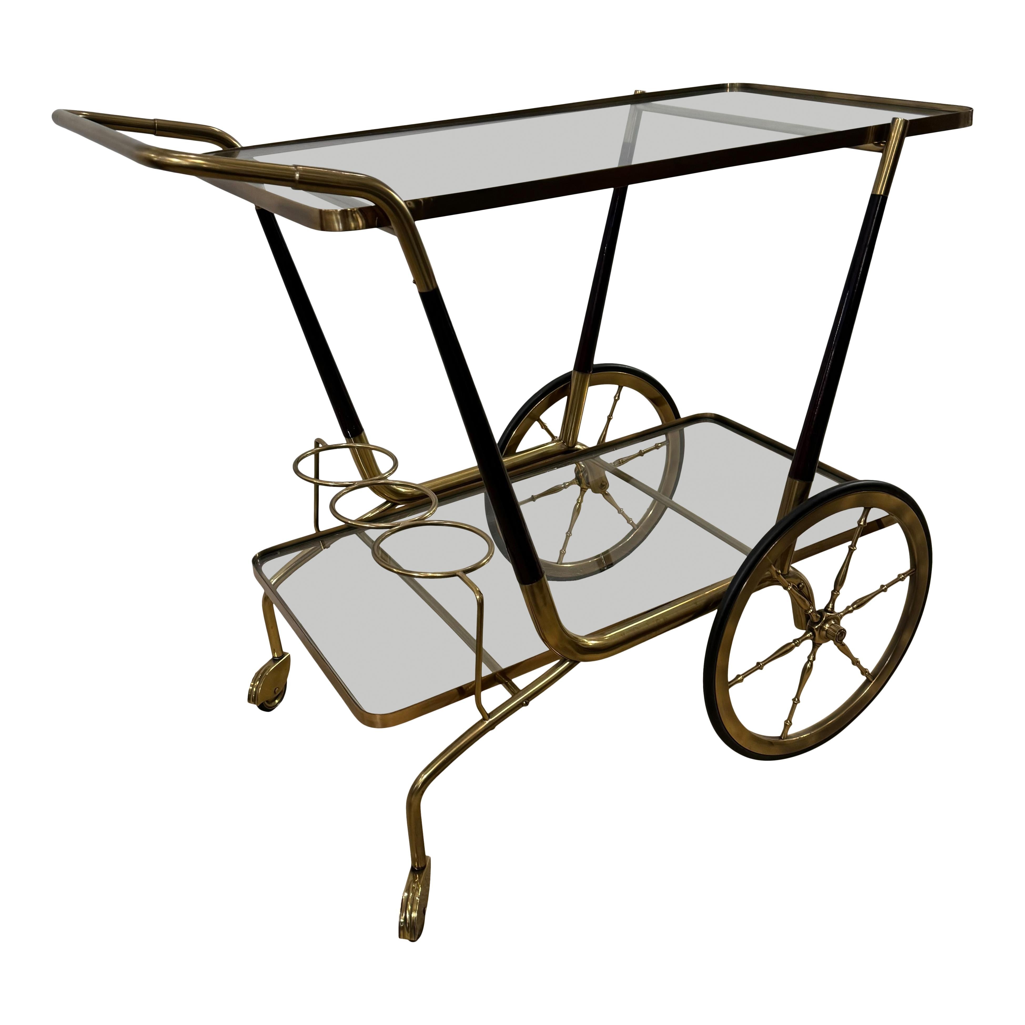 A modernist Italian bar cart. 
Brass with lacquered wood details and two glass shelves.