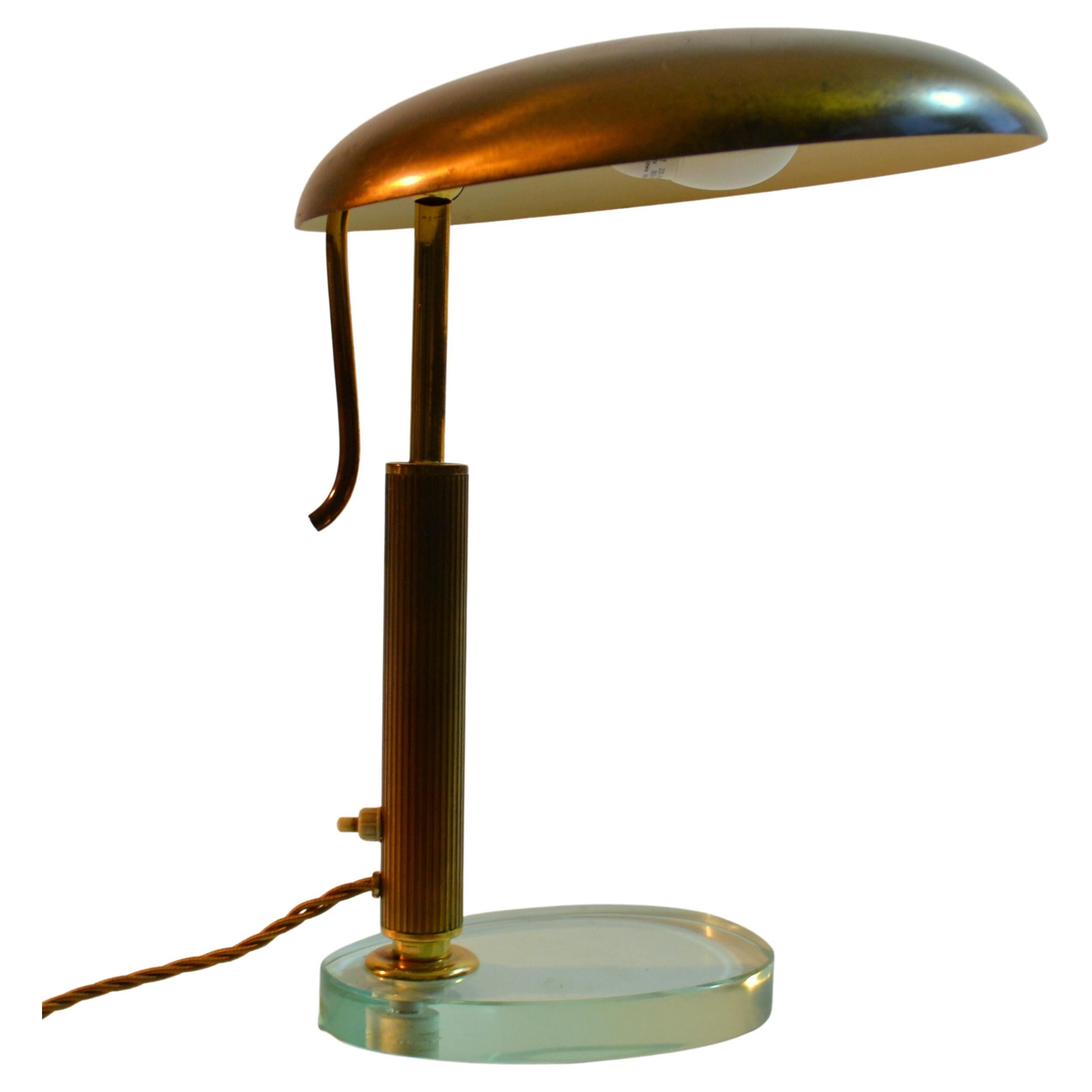 Elegant Italian Modernist 1940's desk or table lamp with adjustable brass shade sits on a glass oval base.
Modernist Desk Lamp attributed to Pietro Chiesa for Fontana Arte  Italy circa 1940.