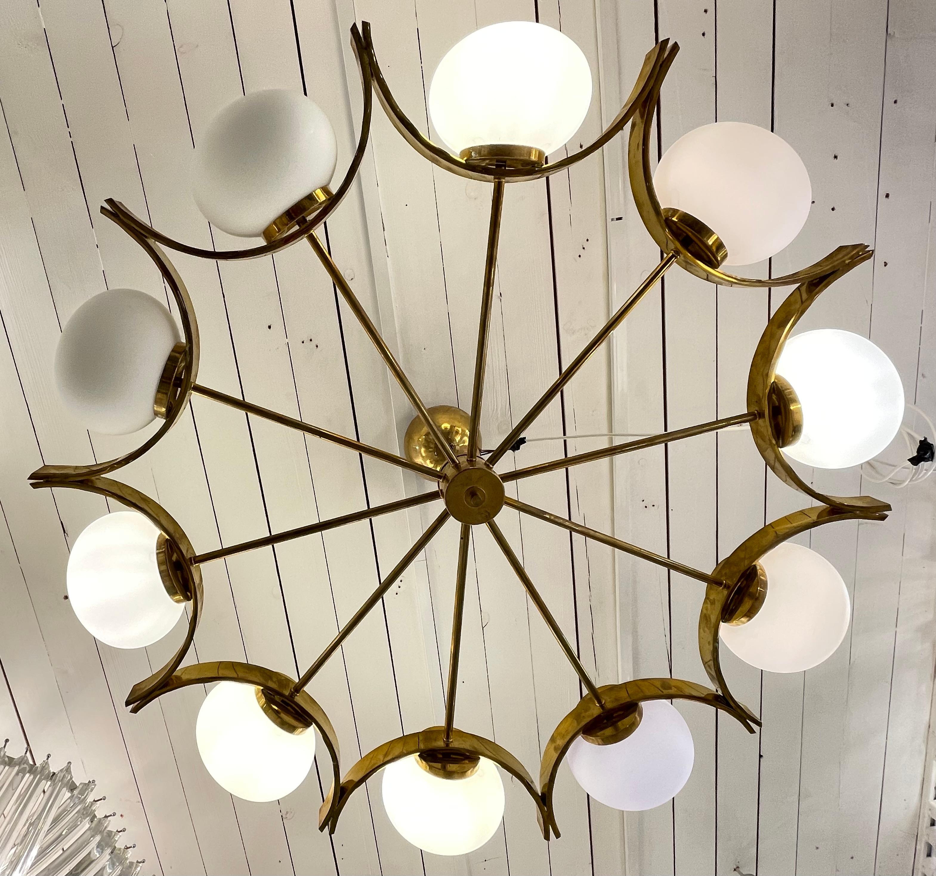 An elegant modernist Italian chandelier in brass with 10 large shades in white frosted glass, circa 1960.