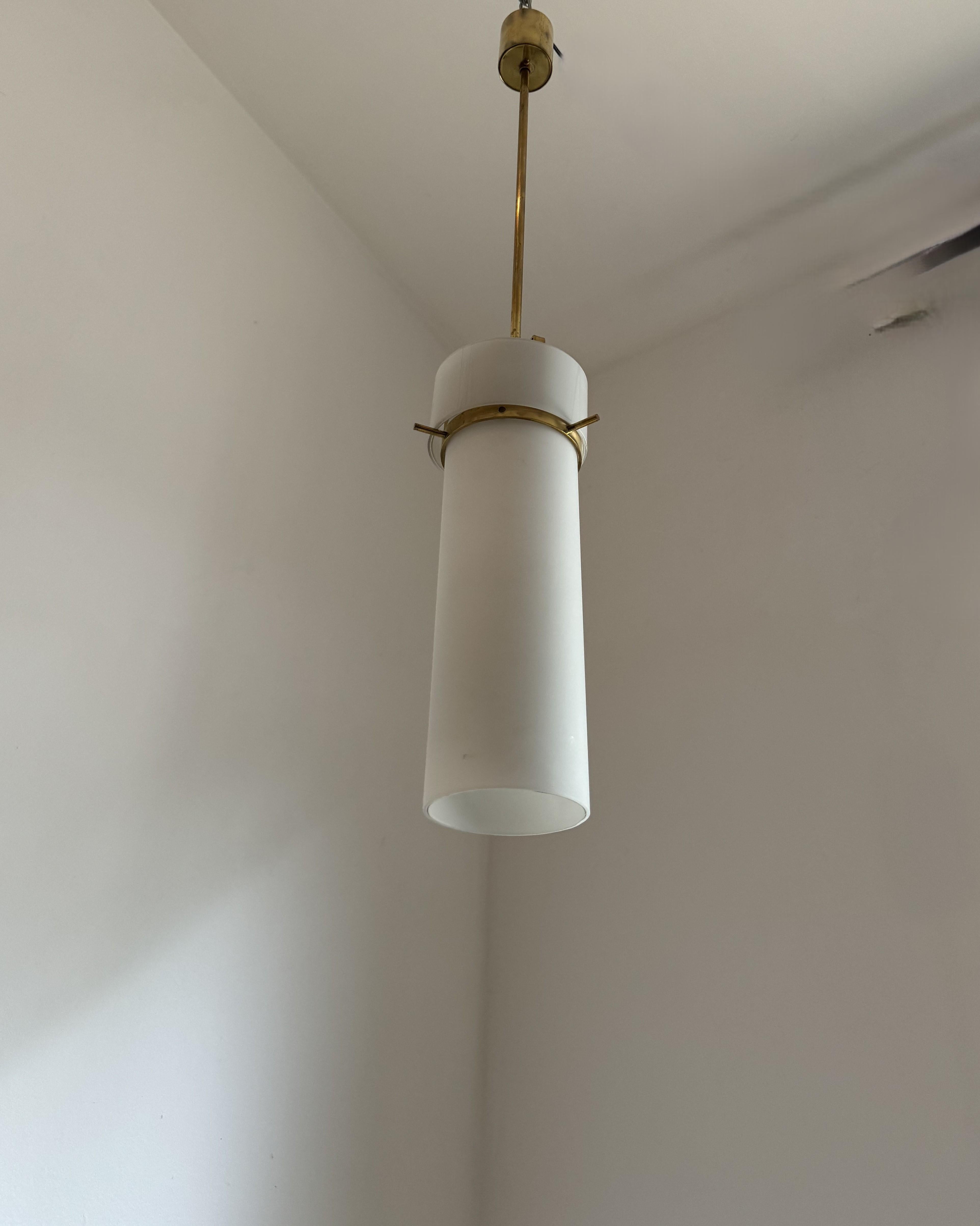 Farol italiano de 1950 fabricado al estilo de las lámparas fabricadas por Stilnovo y diseñadas por Bruno Gatta durante la misma época.
La lámpara consta de un tubo largo de vidrio opalino en acabado mate, un anillo más pequeño y ancho de vidrio