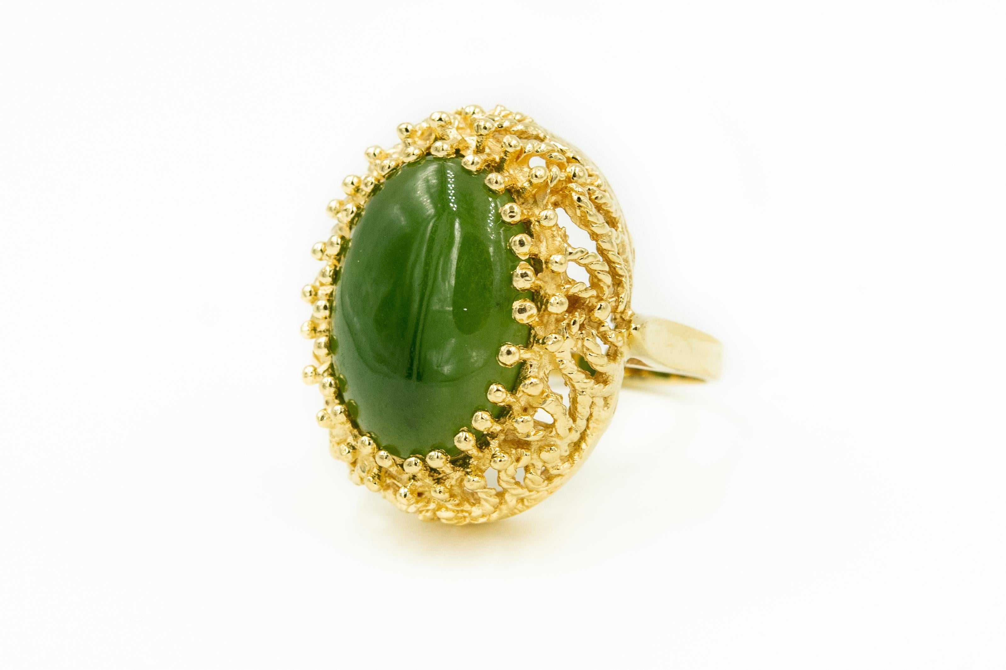 Mid 20th century ring featuring a centrally set cabochon oval piece of green jade prong set in a 14k yellow gold frame that looks like twisted gold rope climbing towards the jade.

US size 6.5

Marked 14k 585